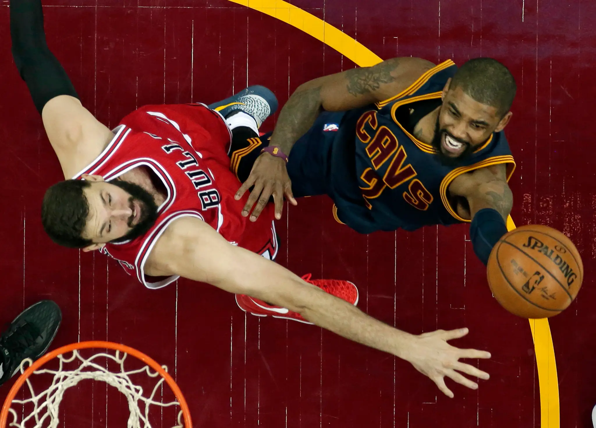 Na snímke vpravo hráč Cavaliers Kyrie Irving strieľa na kôš cez hráča Bulls Nikolu Mirotiča.
