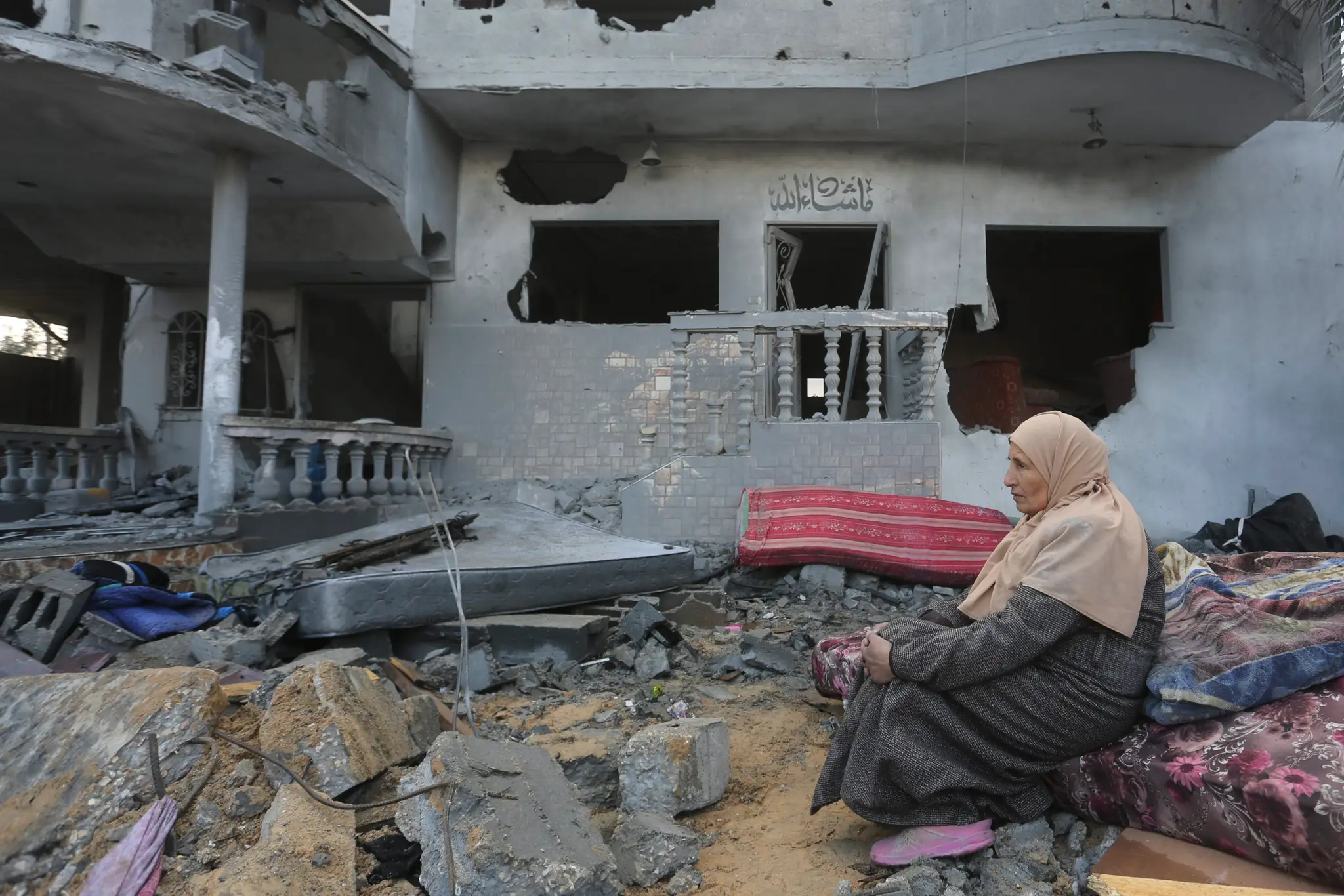 Palestínska žena sedí pri domoch zničených pri izraelskom bombardovaní v pásme Gazy.