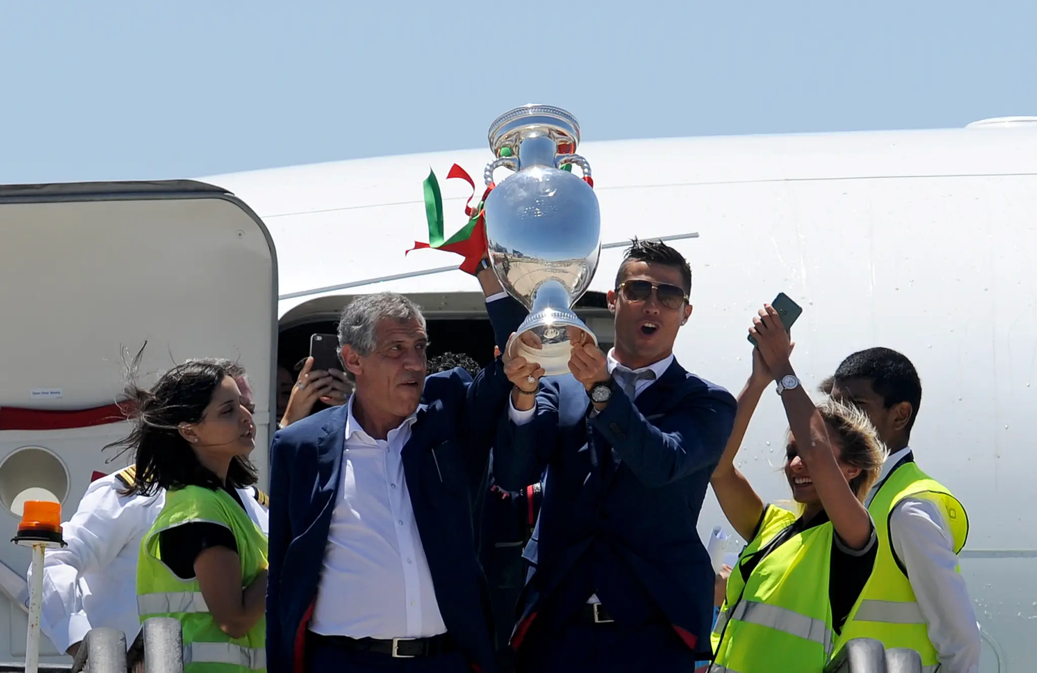 Cristiano Ronaldo a tréner Fernando Santos zdvíhajú pohárovú trofej majstrov Európy po prílete na letisko v Lisabone.