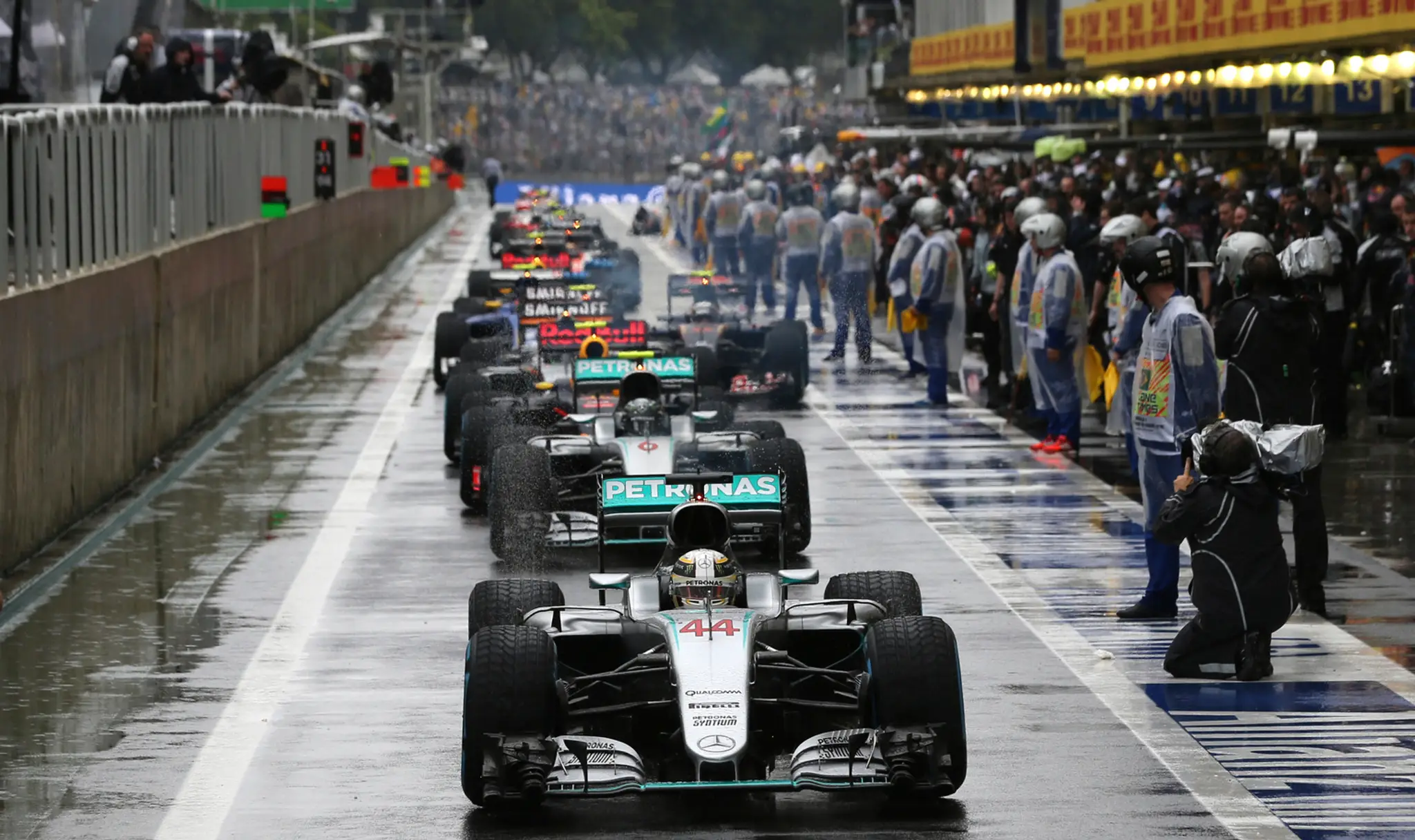 Lewis Hamilton stojí na čele monopostov v boxovej uličke počas prerušenia preteku pre nehodou Kimiho Räikkönnena.