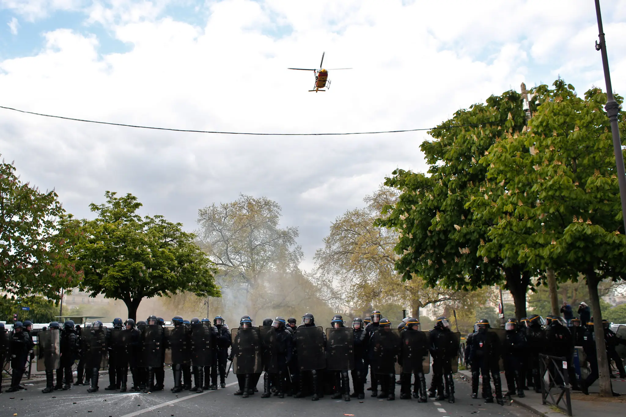 Vrtuľník letí nad príslušníkmi poriadkovej polície v Paríži.