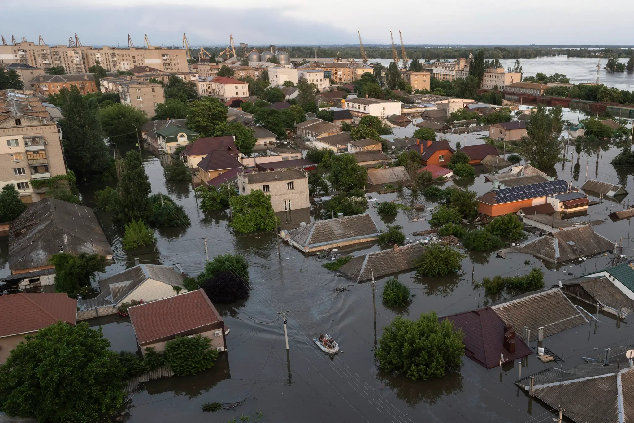 Ľudia jazdia na gumených člnoch v zaplavenej štvrti Chersonu na Ukrajine.