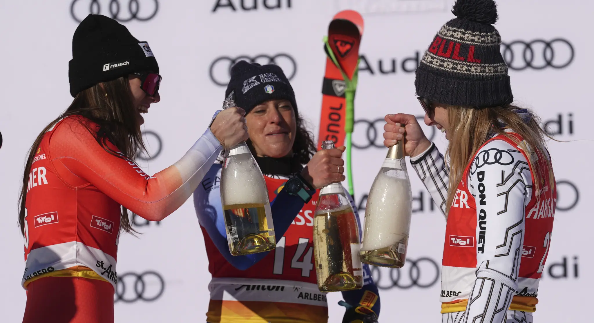 Talianka Federica Brignoneová (uprostred) pózuje so šampanským na pódiu po triumfe v zjazde Svetového pohára alpských lyžiarok v rakúskom stredisku St. Anton