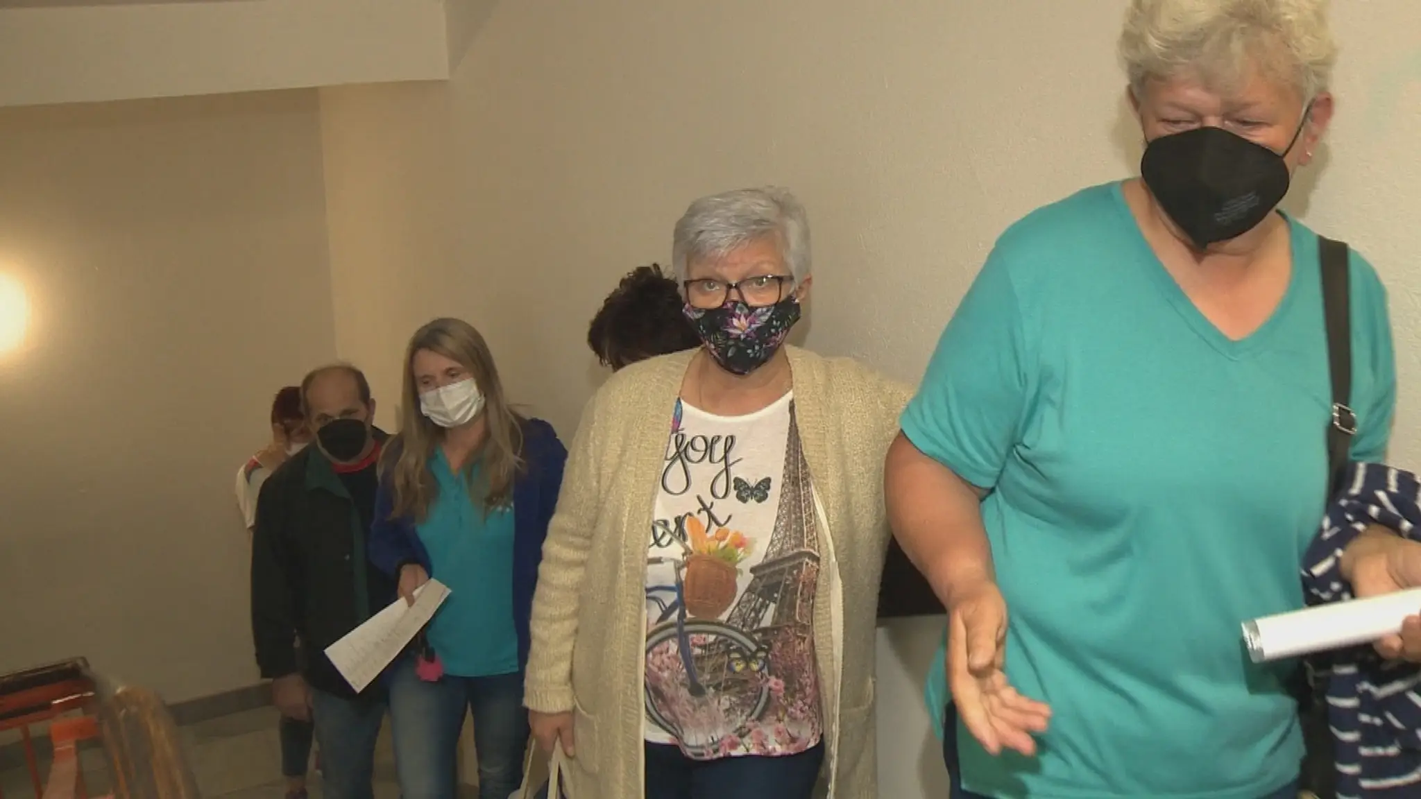 Ľudia čakajú na očkovanie v rade na schodoch.