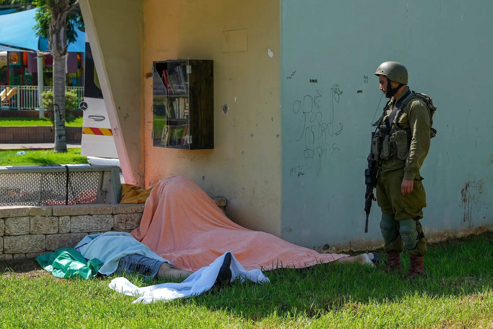 Izraelský vojak stojí pri telách Izraelčanov zabitých palestínskymi ozbrojenými militantmi.