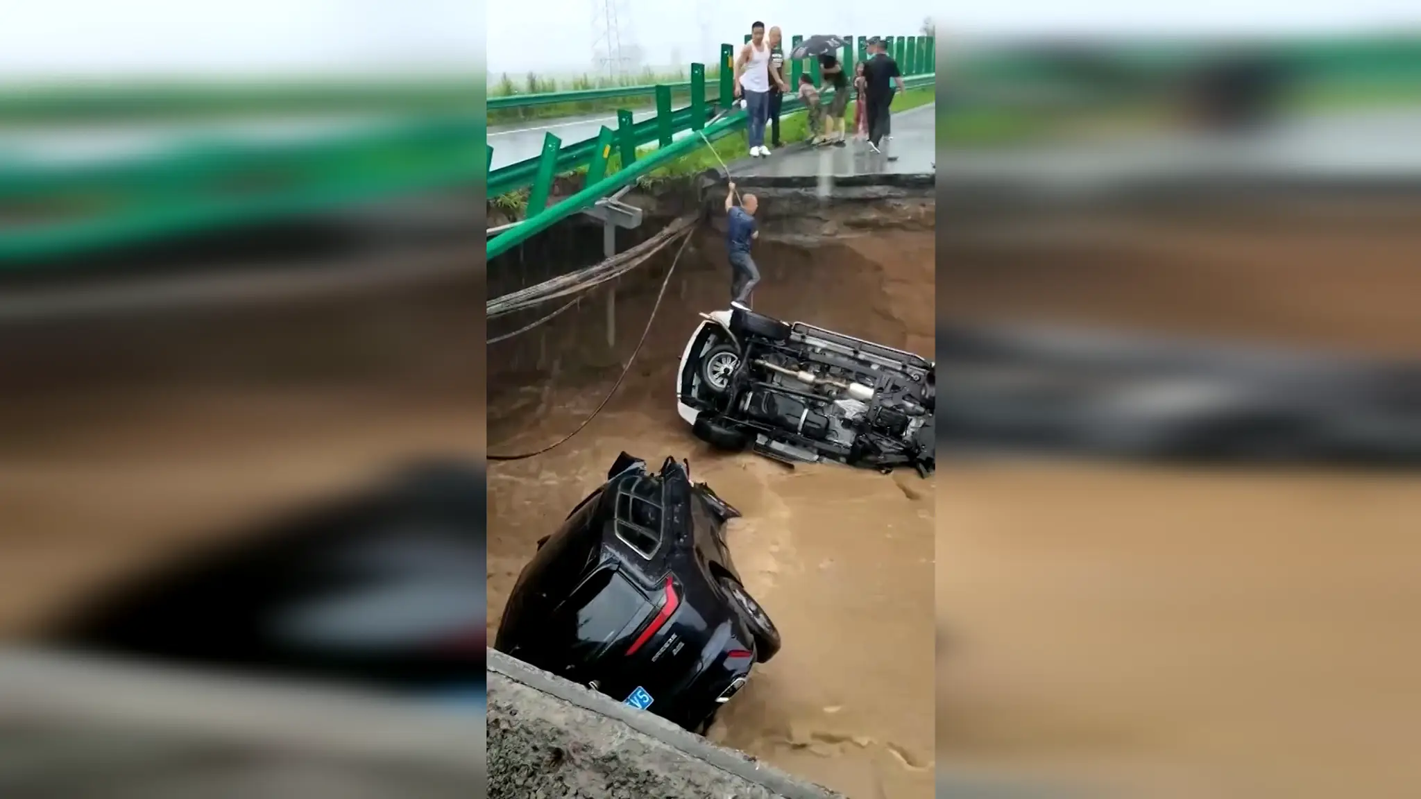 Muž lezie po lane po tom, ako jeho auto spadlo do jamy.