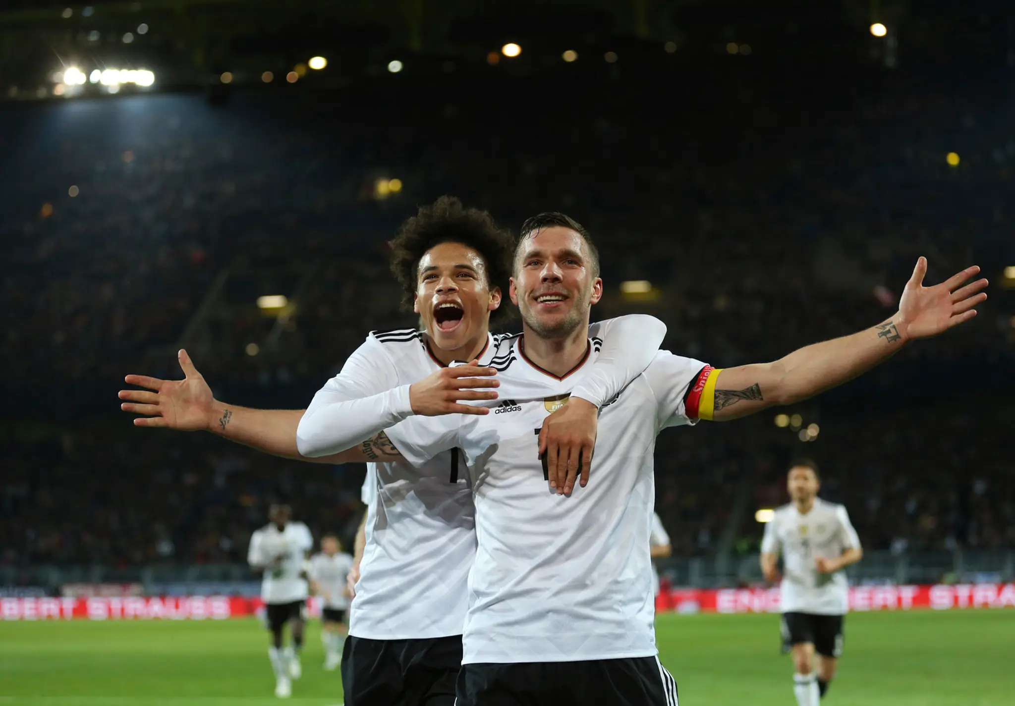 Lukas Podolski oslavuje so spoluhráčom Leroyom Saném svoj gól.