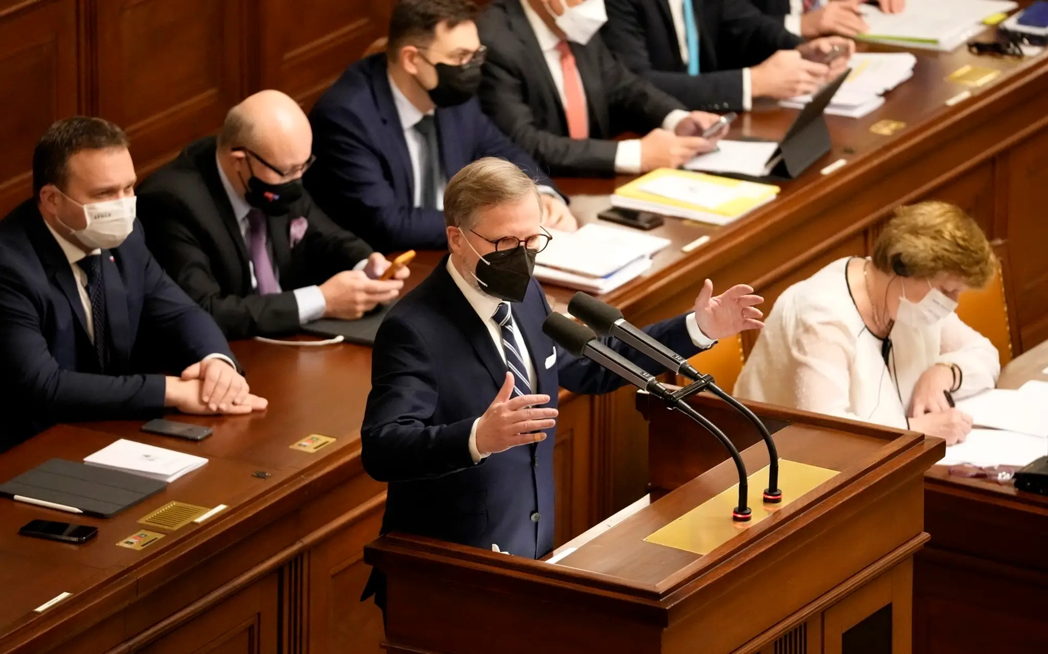 Český premiér Petr Fiala (ODS) stojí za rečníckym pultom počas zasadnutia parlamentu.
