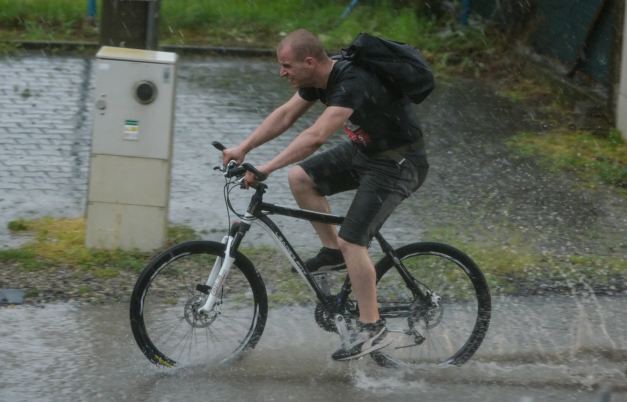 Cyklista jazdí po ceste, kde voda nestíha odtekať v dôsledku silnej búrky v Bratislave.