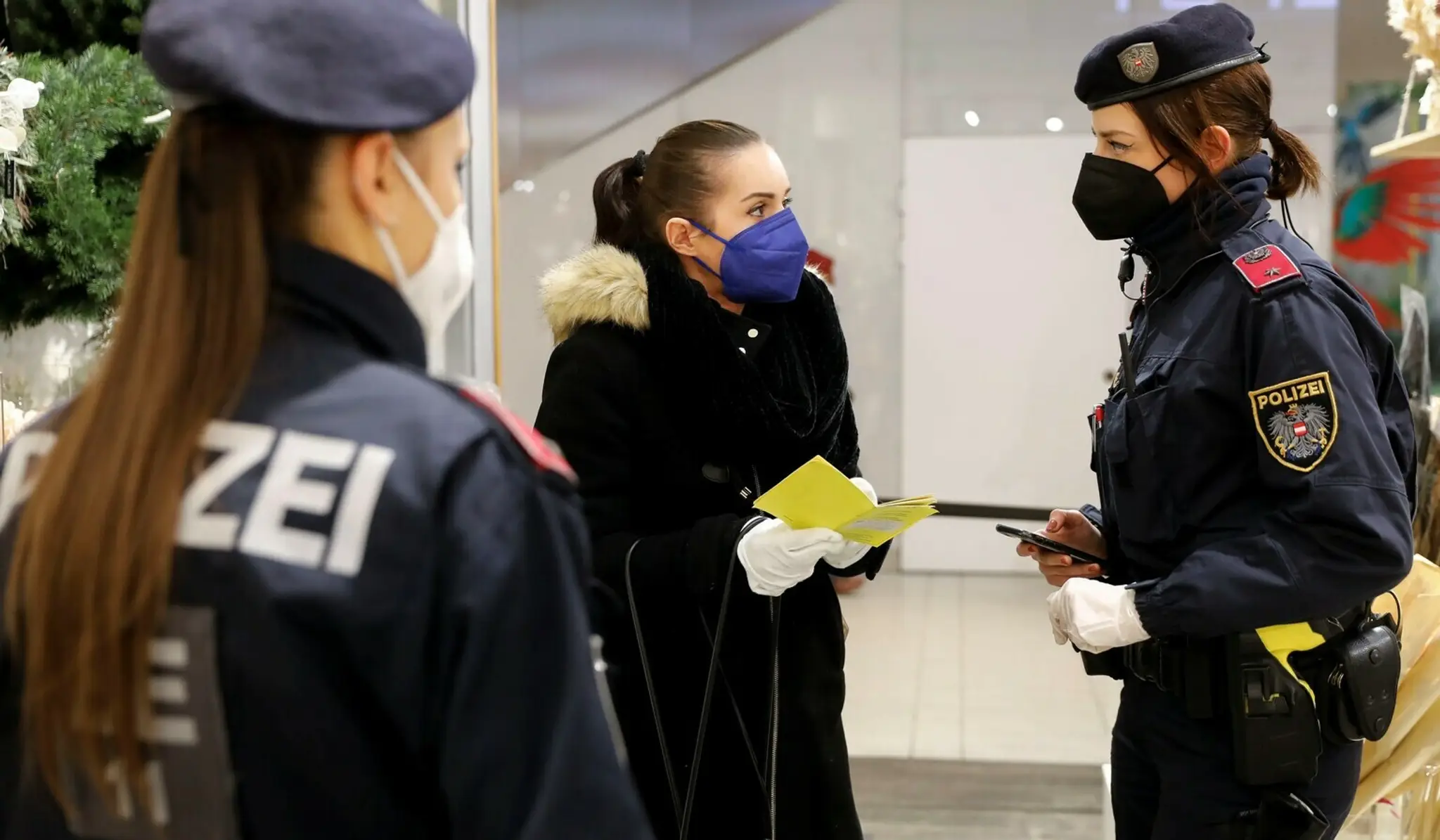 Policajtka kontroluje očkovací preukaz zákazníčky vo Viedni.