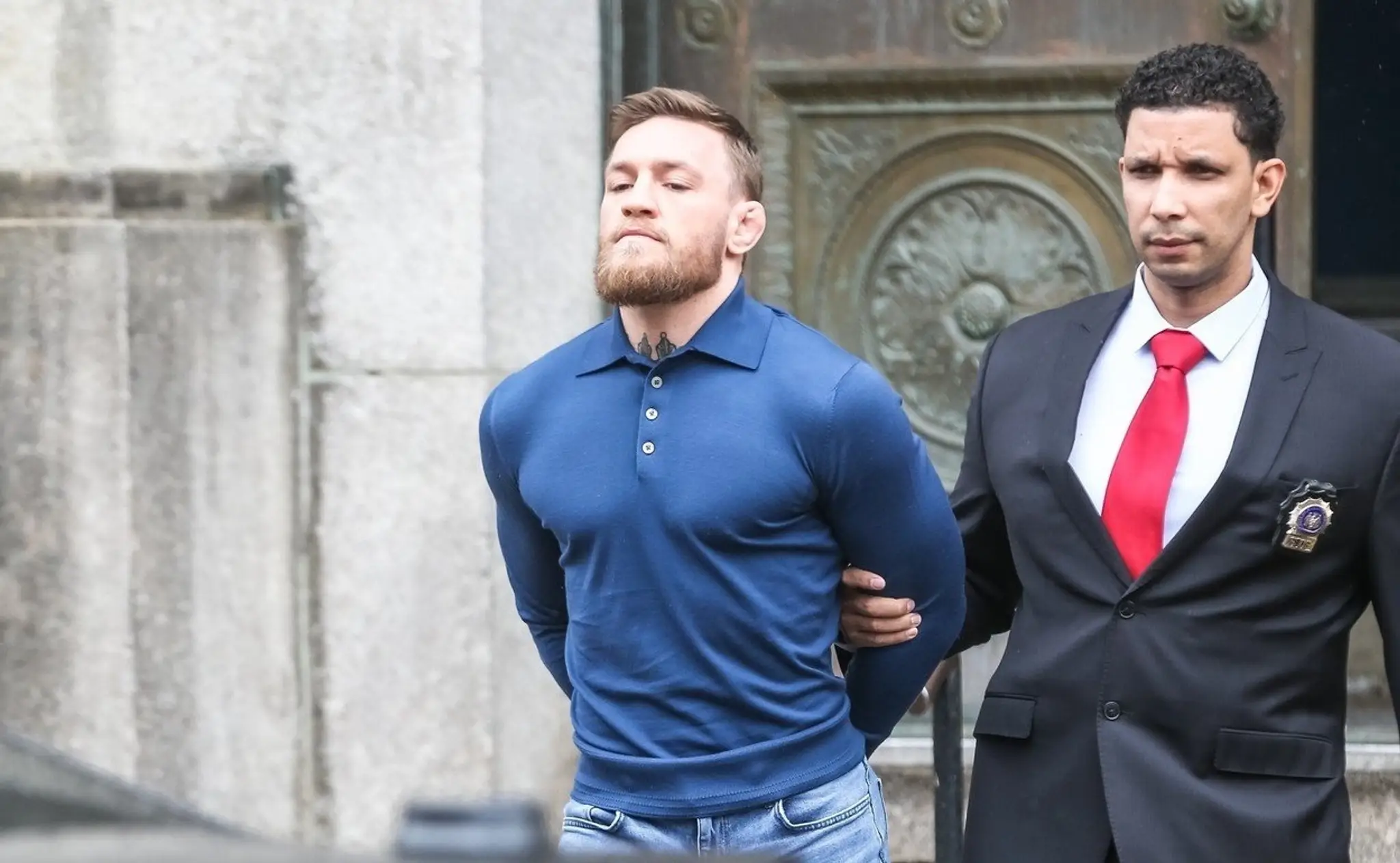 Policajt odvádza McGregora do súdnej siene.