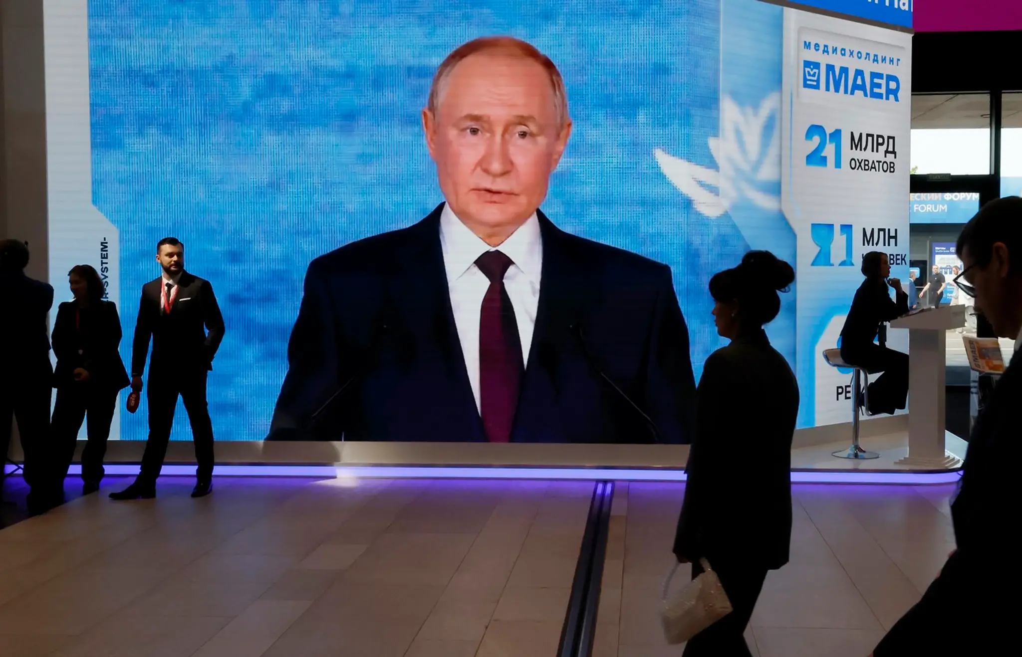 Účastníci prechádzajú popri veľkej obrazovke, na ktorej je zobrazený ruský prezident Vladimir Putin, počas Medzinárodného ekonomického fóra v Petrohrade.