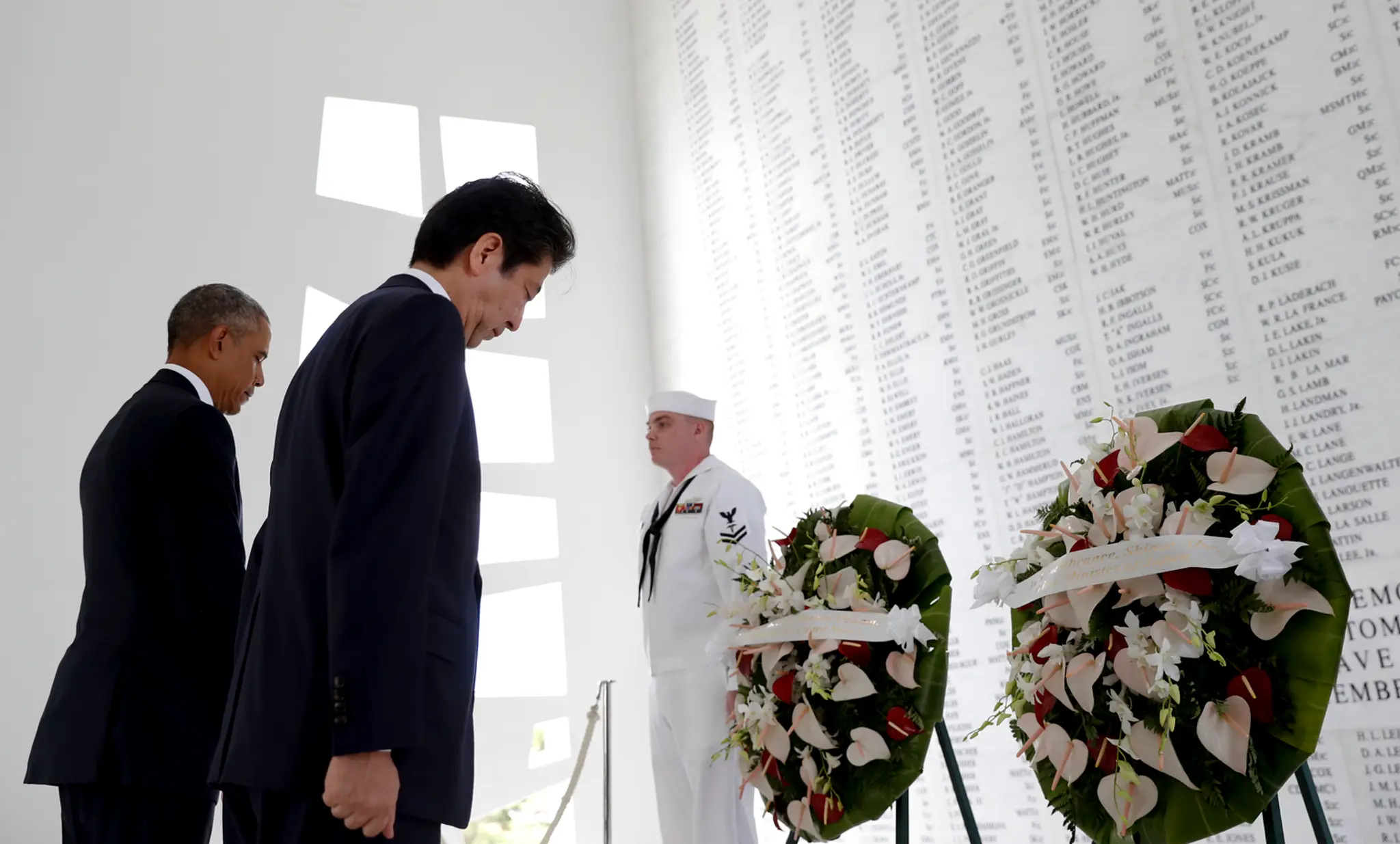 Japonský premiér Šinzó Abe a prezident USA Barack Obama sa skláňajú počas kladenia vencov pri pamätníku nad vrakom lodi Arizona.