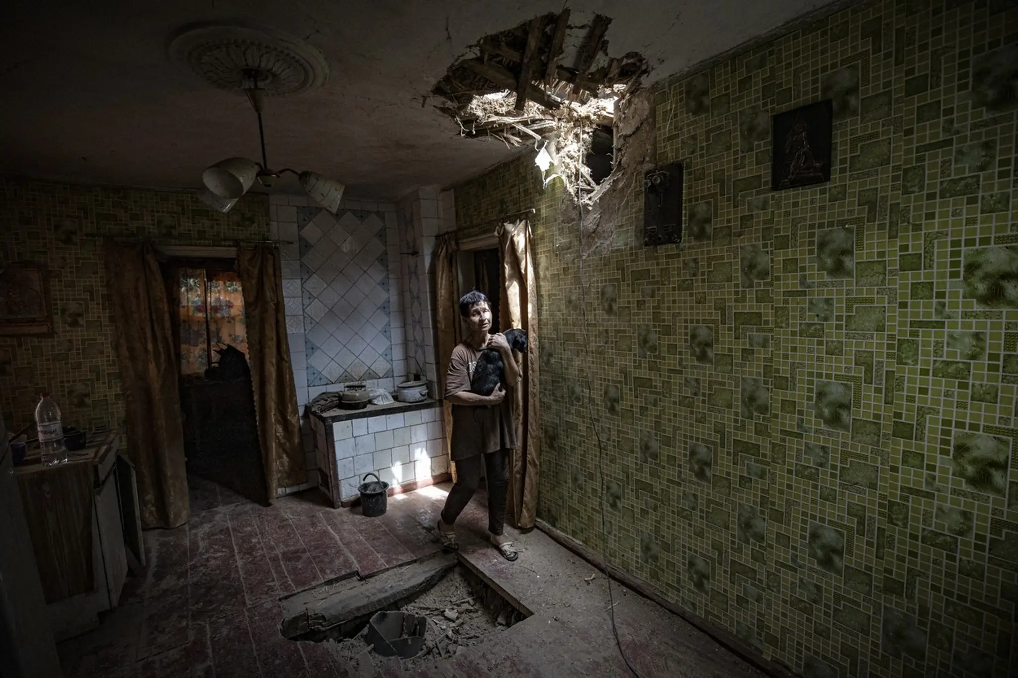 Nina Ovcarovaninová (61) sa pozerá cez dieru v v strope po nevybuchnutej ruskej rakete. (25. 7. 2022, Bachmut, Donetská oblasť) 