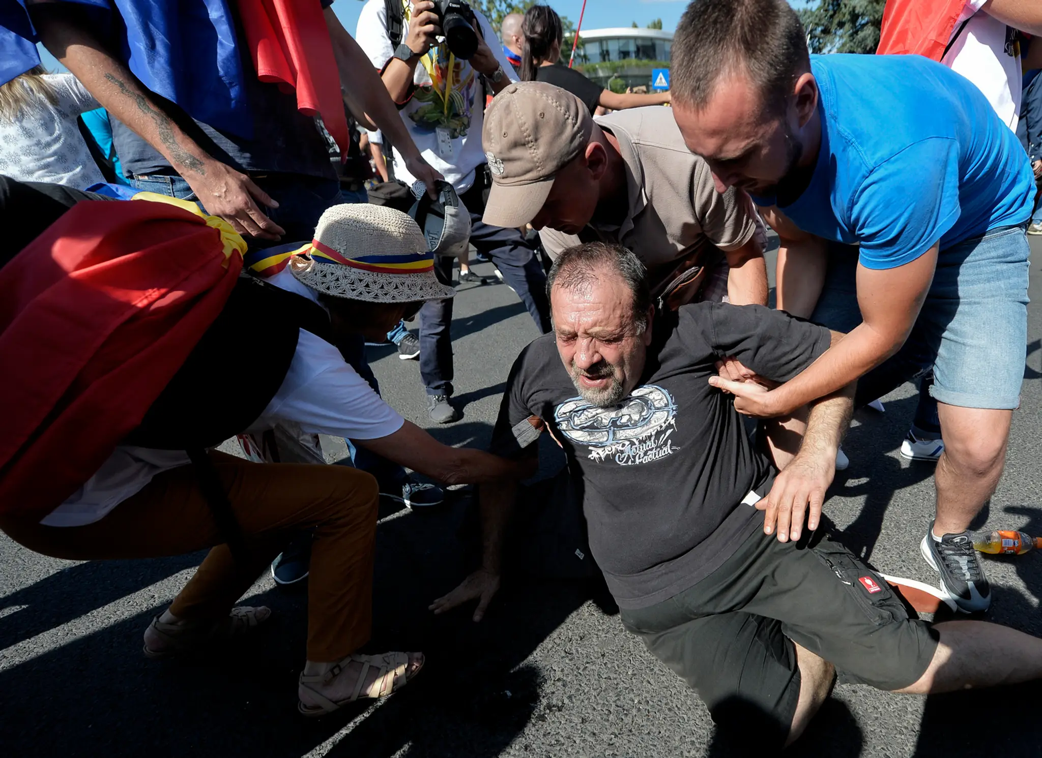 Demonštranti pomáhajú vstať mužovi, ktorý spadol, keď sa pokúšal prejsť cez zástup policajtov na protivládnom proteste v Bukureš