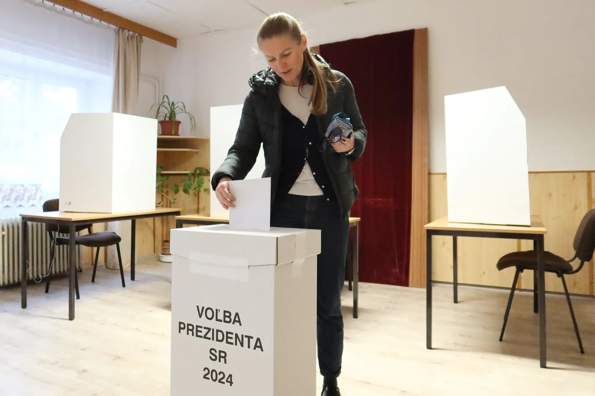Jedna z prvých voličiek v bratislavskej Devínskej Novej Vsi vhadzuje obálku s hlasovacím lístkom do volebnej schránky.