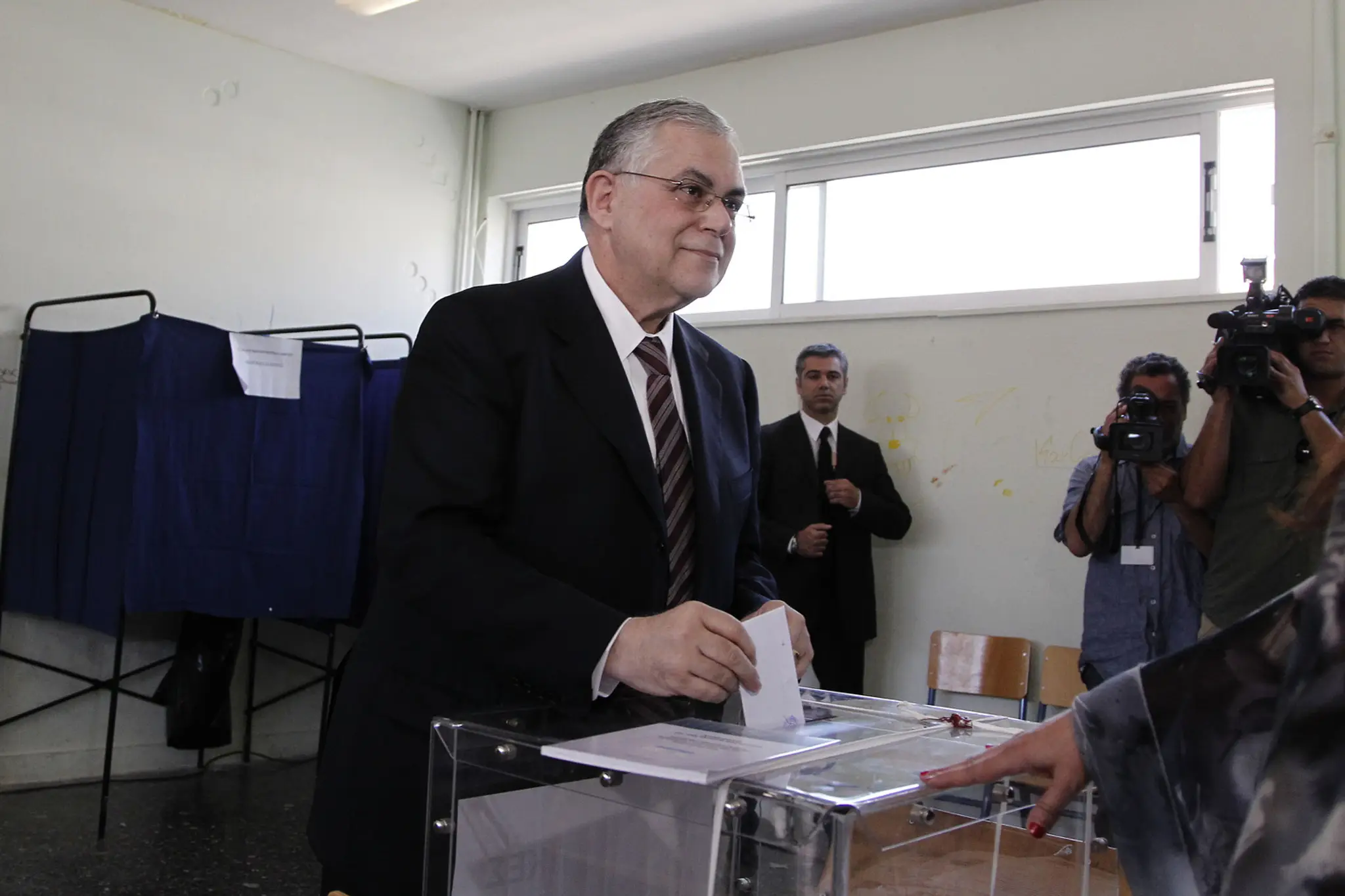 Grécky vtedy ešte premiér Lucas Papademos hlasuje počas parlamentných volieb 6. mája 2012 v Aténach. (archív)