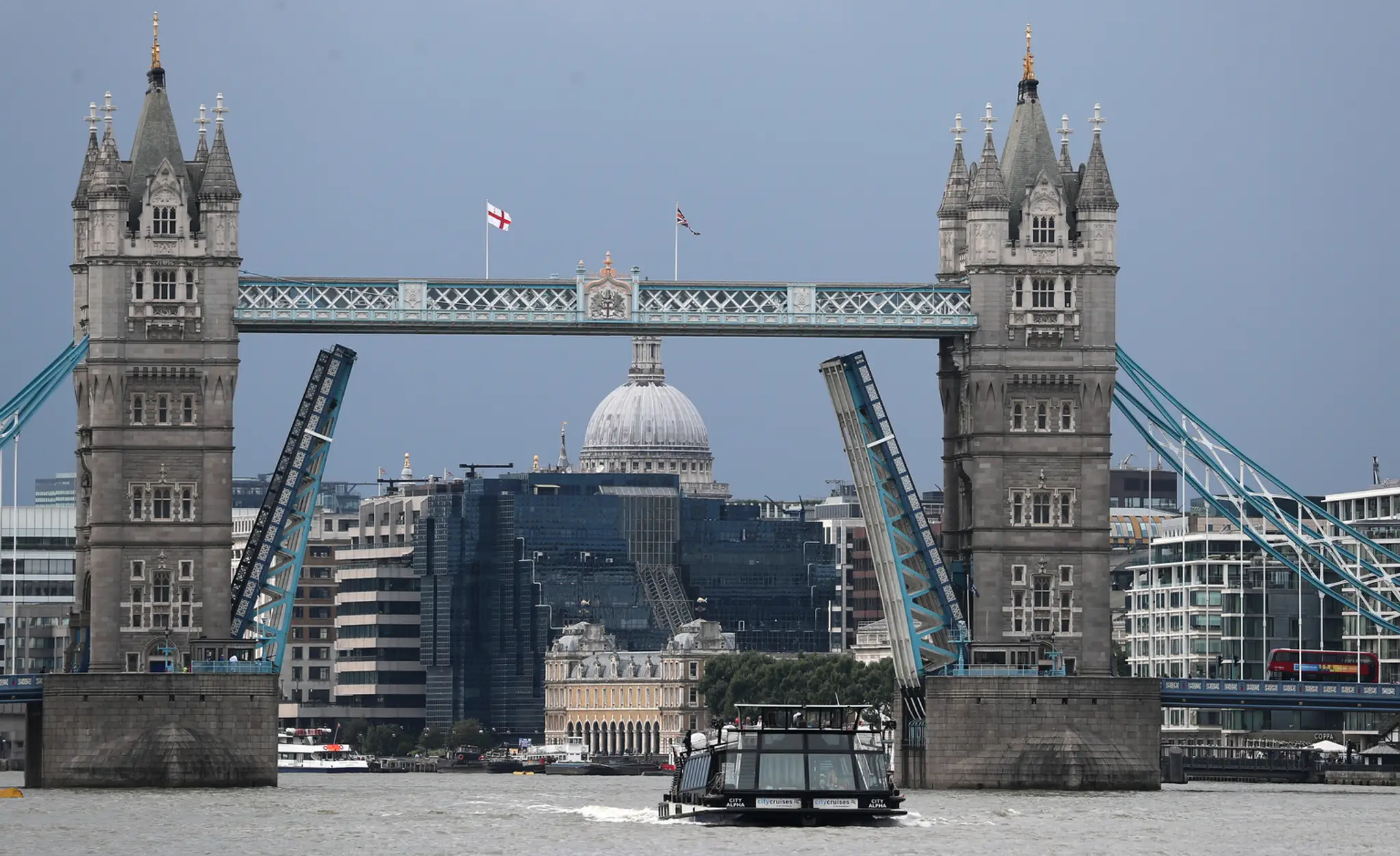 Čln pláva na rieke Temža pod zaseknutým zdvíhacím mostom Tower Bridge.
