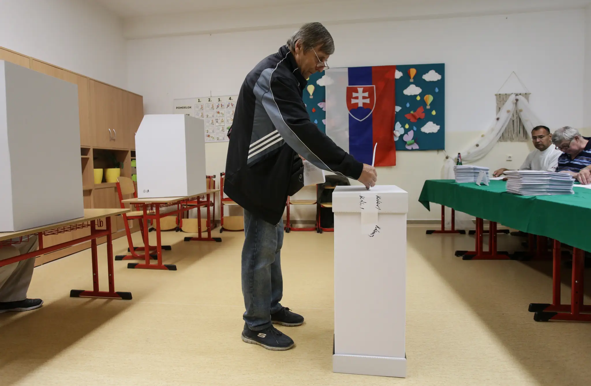 Volič vhadzuje obálku s hlasovacím lístkom do volebnej schránky v priestoroch Základnej školy na Karpatskej ulici v Žiline.
