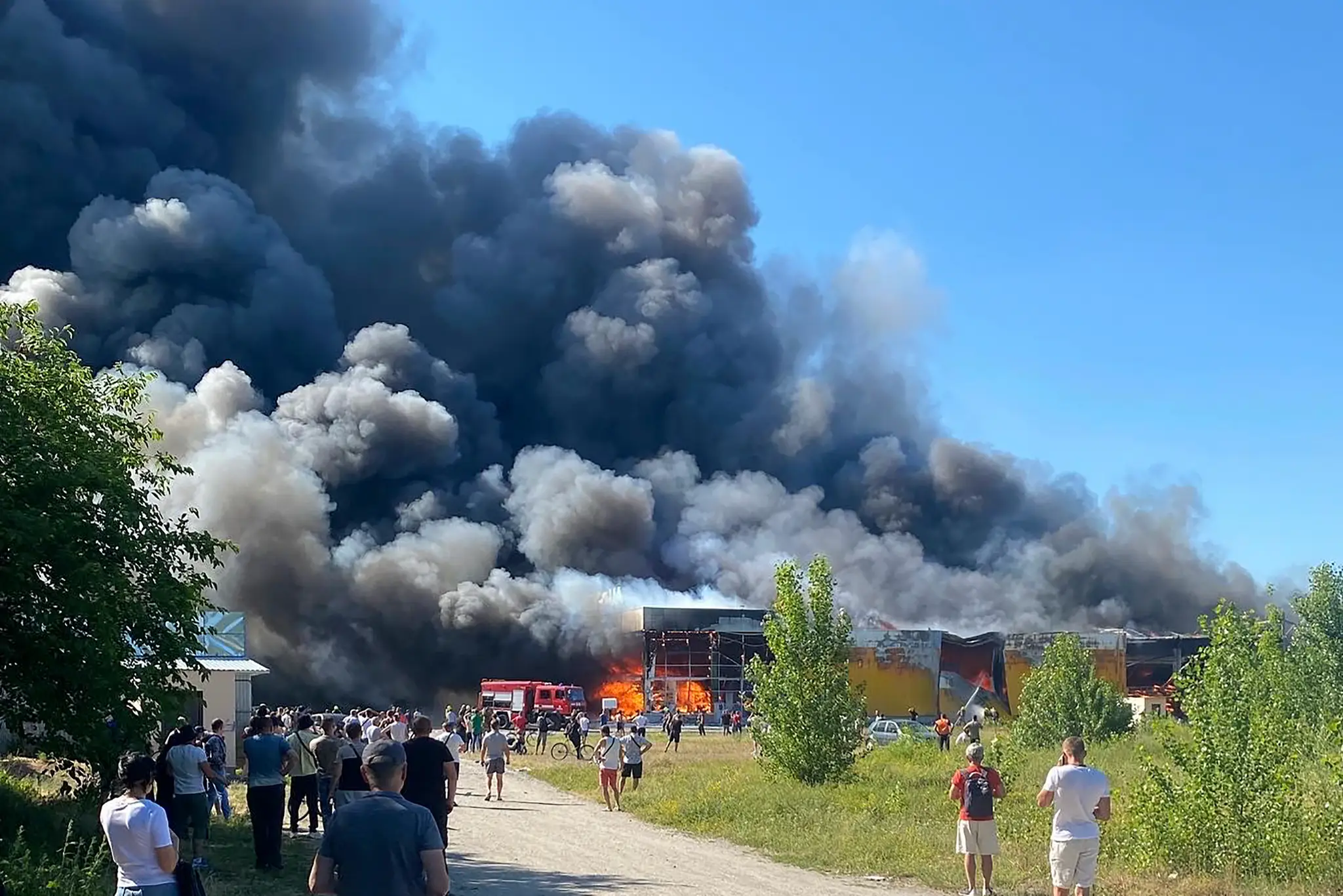 Ľudia sledujú hustý čierny dym  po ruskom raketovom útoku na nákupné centrum v ukrajinskom meste Kremenčuk.