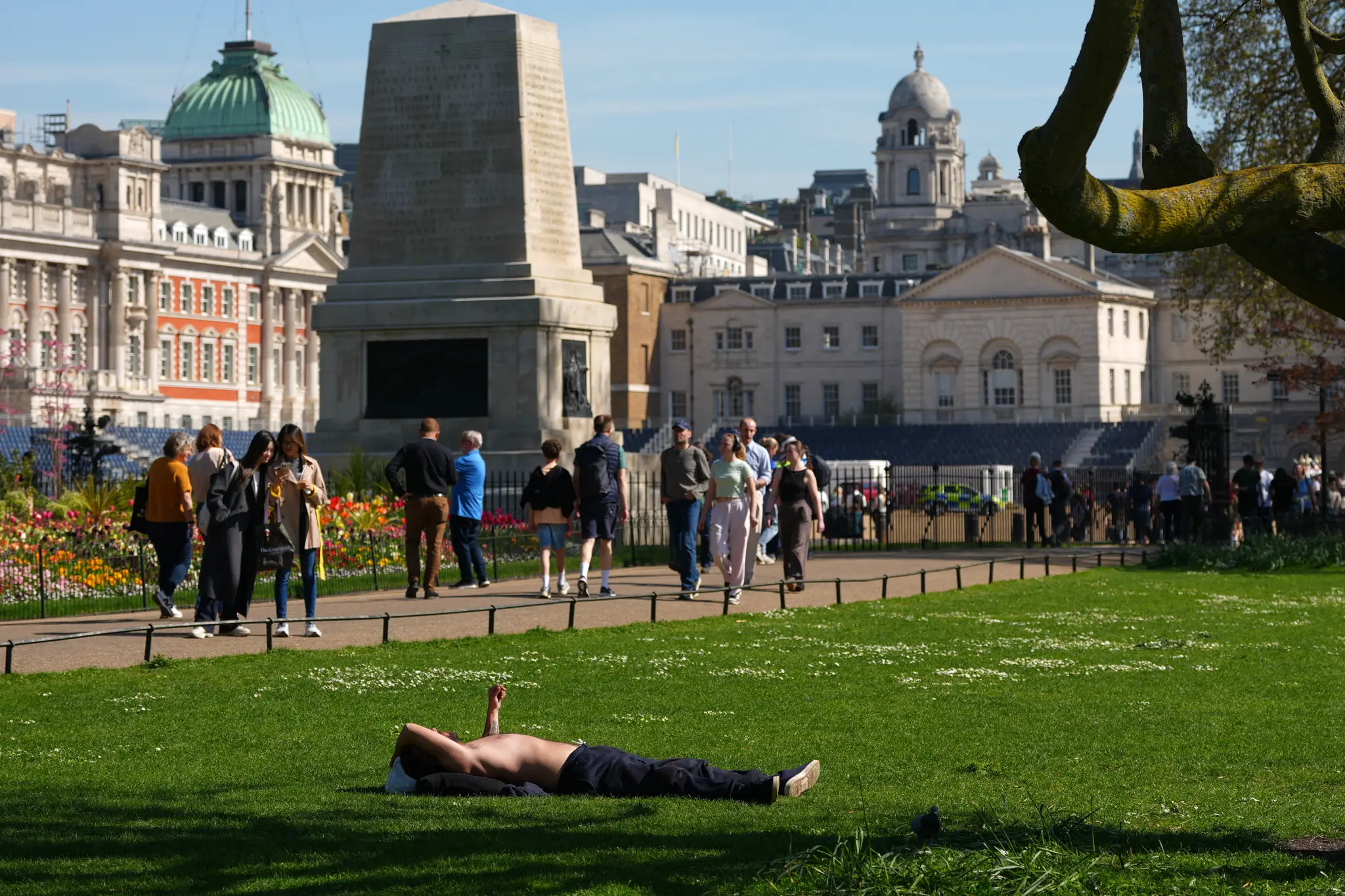 N snímke muž sa opaľuje počas slnečného dňa v parku St James's Park v Londýne.