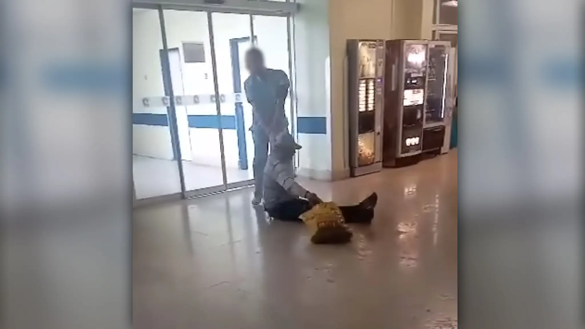 Zdravotník chytil bezdomovca za ruku a ťahá ho po zemi.