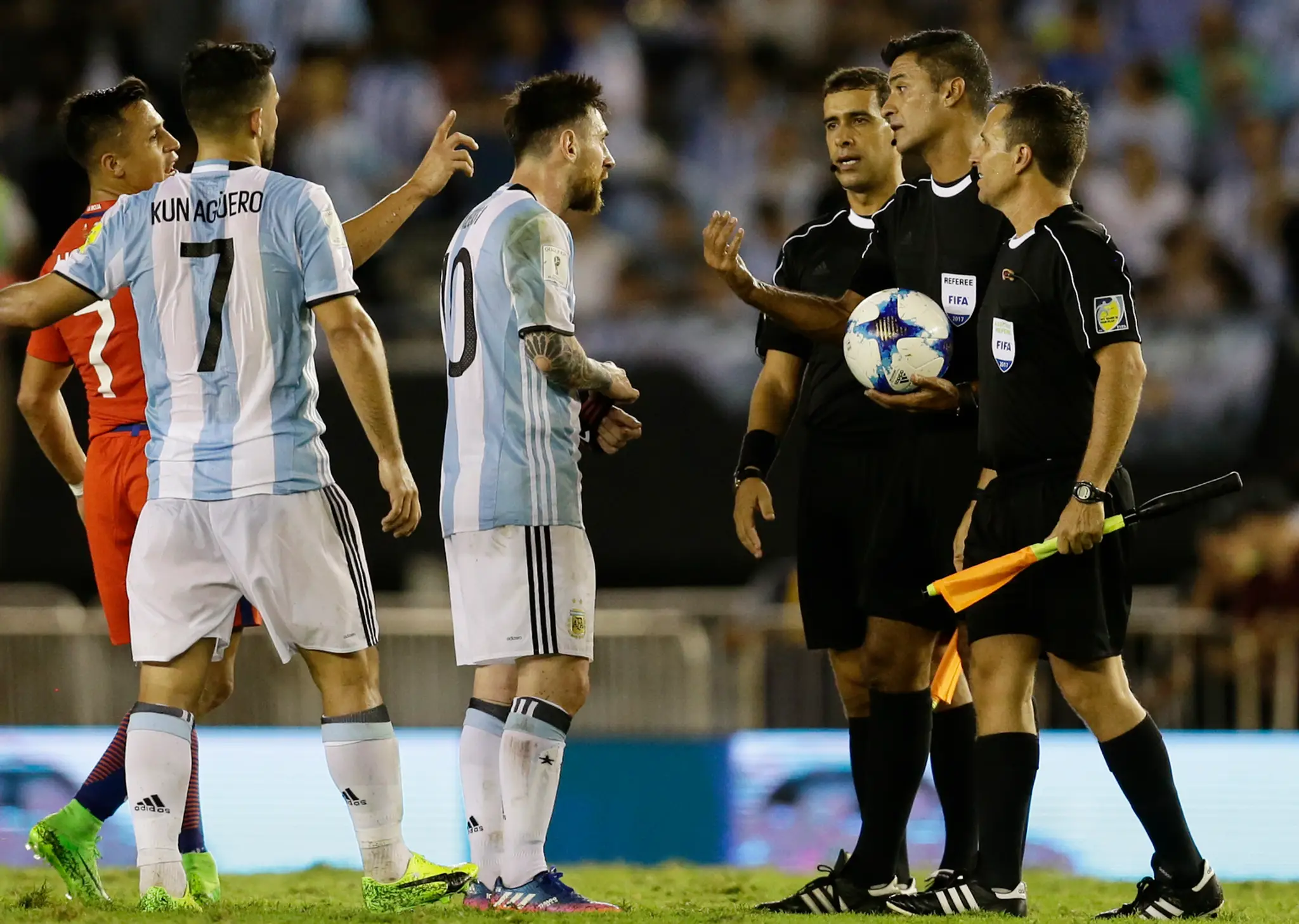 Lionel Messi (v strede) z Argentíny v debate s čiarovým arbitrom Sandrom Riccim v dueli kvalifikácie proti Čile.