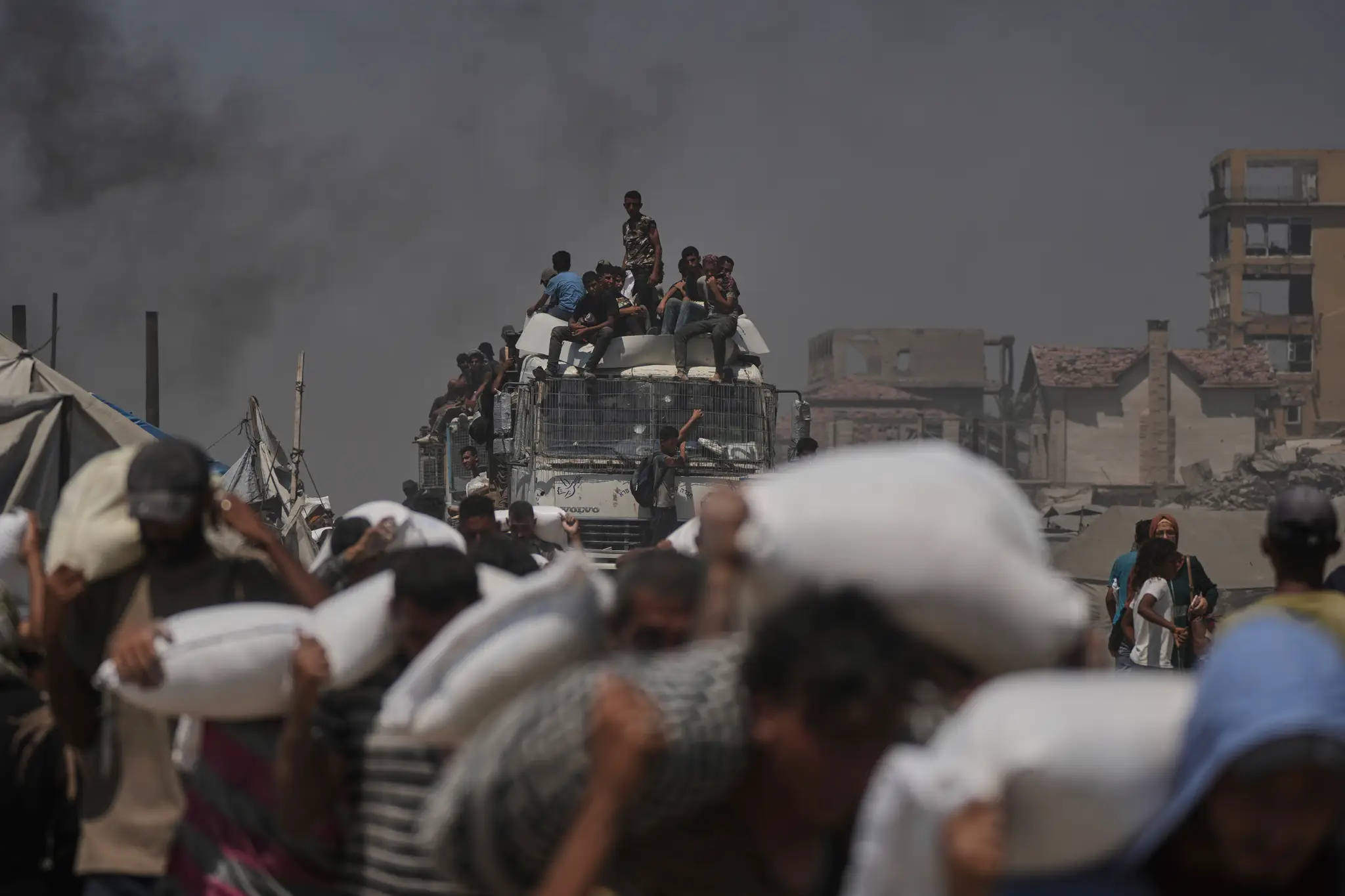 Palestínčania si odnášajú vrecia s múkou, ktoré priviezli kamióny s humanitárnou pomocou do mesta Gaza.