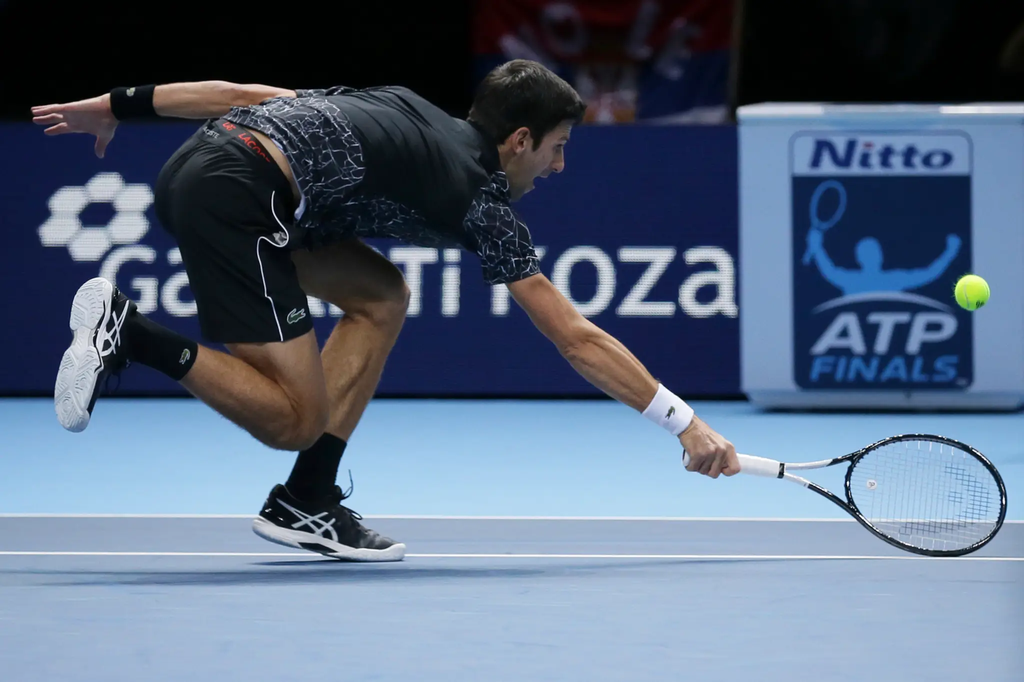 Novak Djokovič odvracia ťažkú loptu od Johna Isnera.
