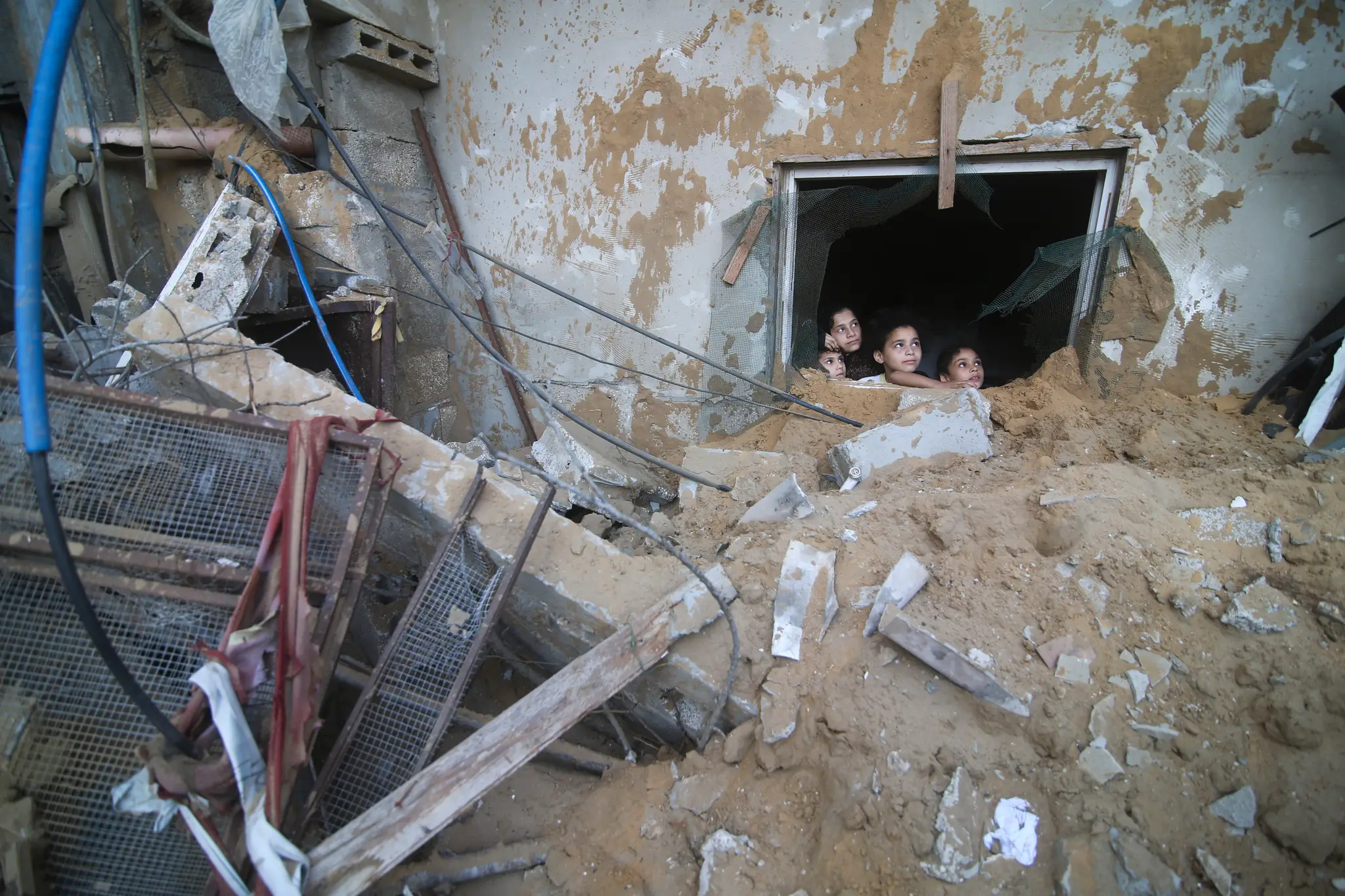 Palestínske deti sa pozerajú zo zničeného domu po raketovom útoku izraelskej armády v palestinskom meste v južnom cípe Pásma Gazy.