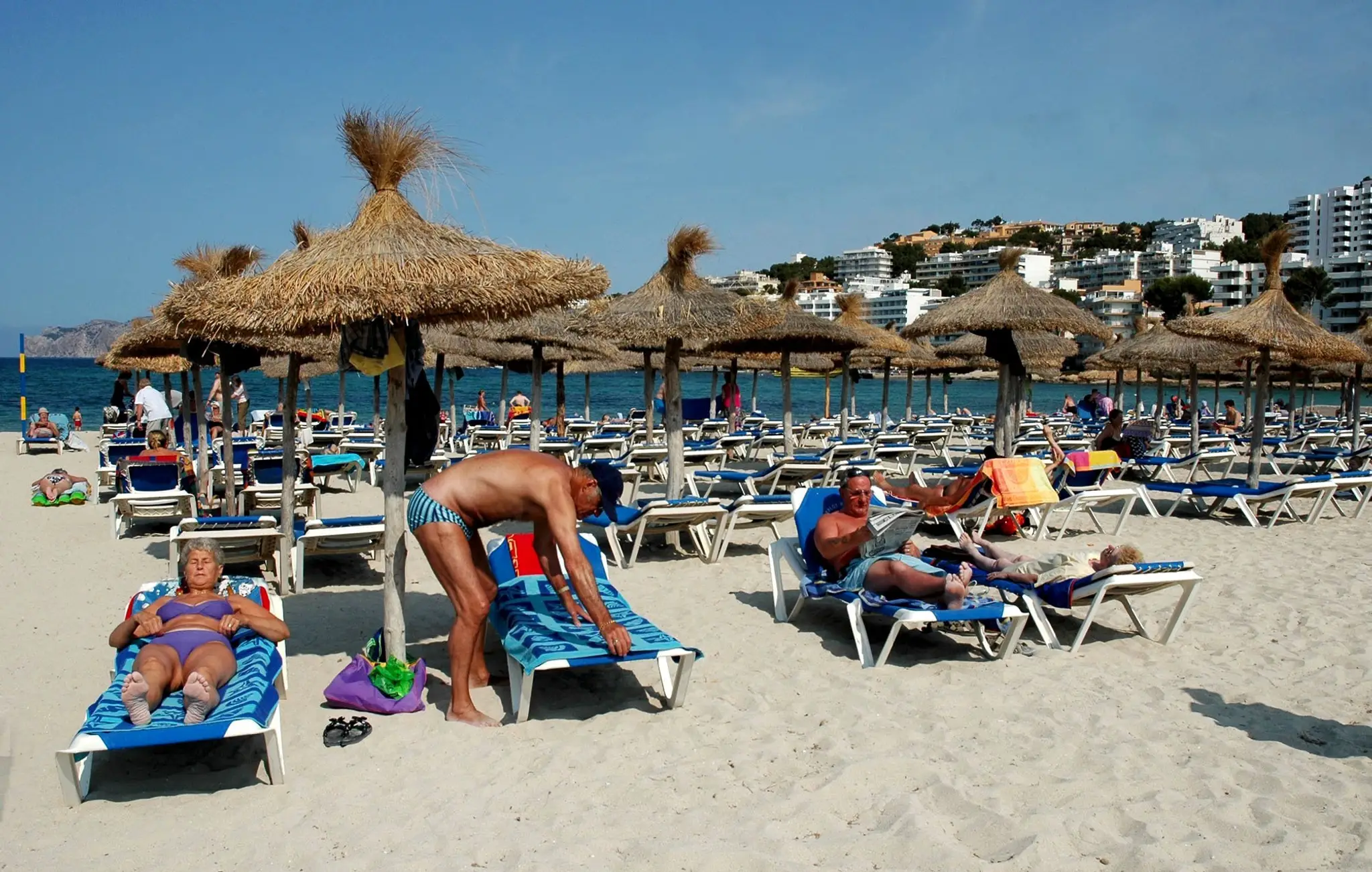 Turisti odpočívajú na piesočnatej pláži v Palme, hlavnom meste španielskeho ostrova Malorka.