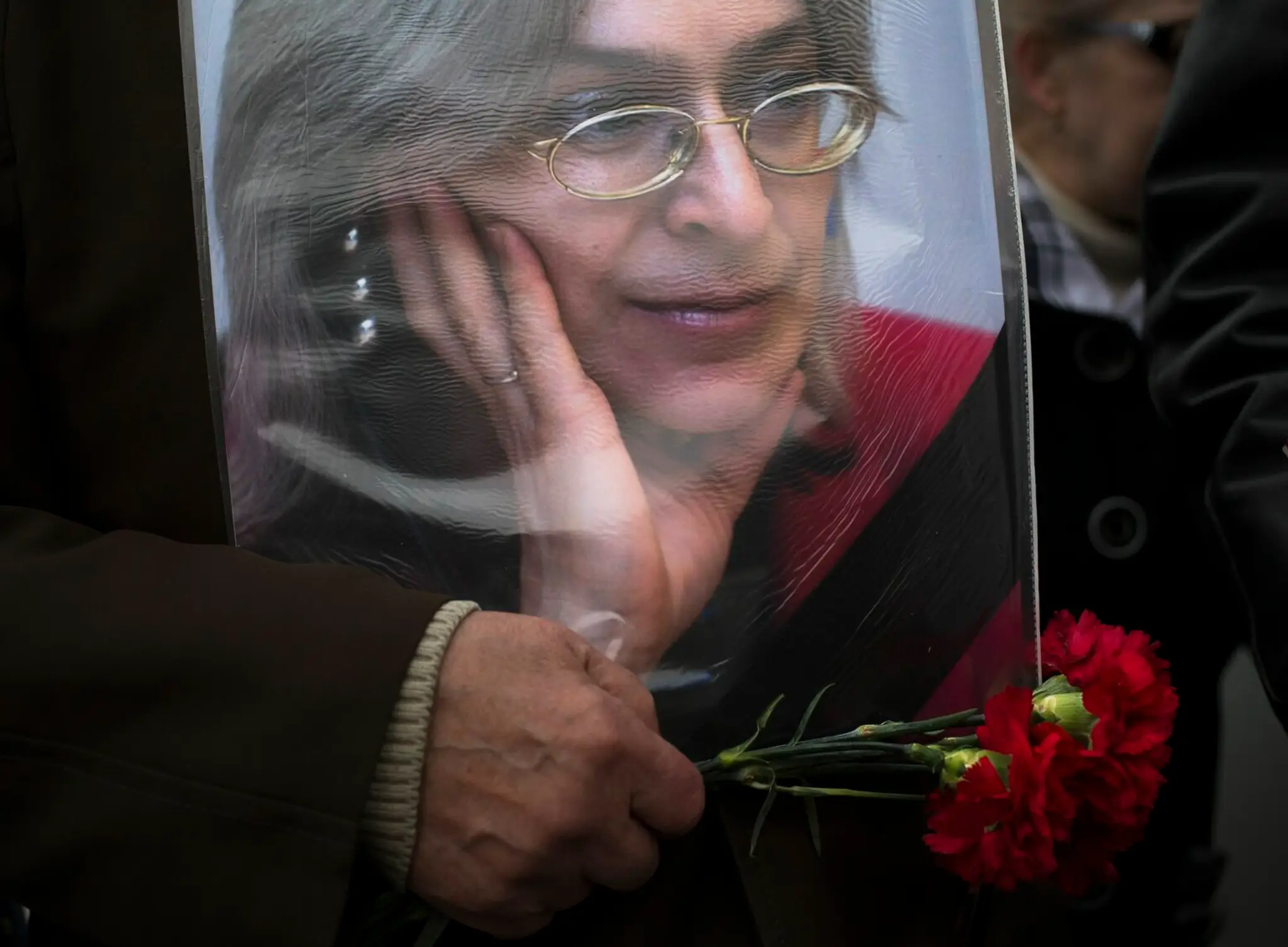Staršia žena drží portrét zosnulej novinárky Anny Politkovskej.
