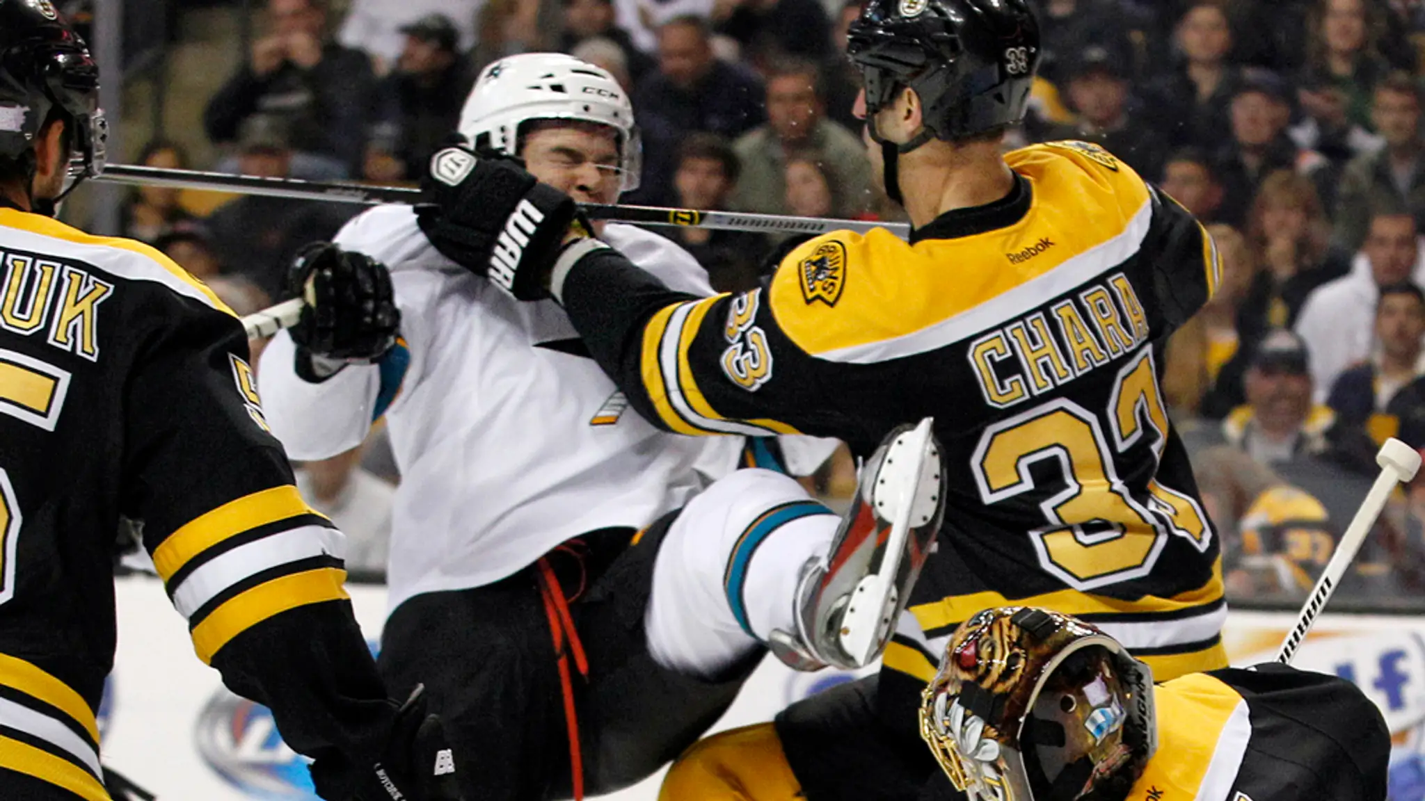 Kapitán Bostonu Bruins Zdeno Chára (druhý vpravo) a hráč San Jose Sharks Čech Tomáš Hertl v súboji pred brankárom Bostonu Tuukko
