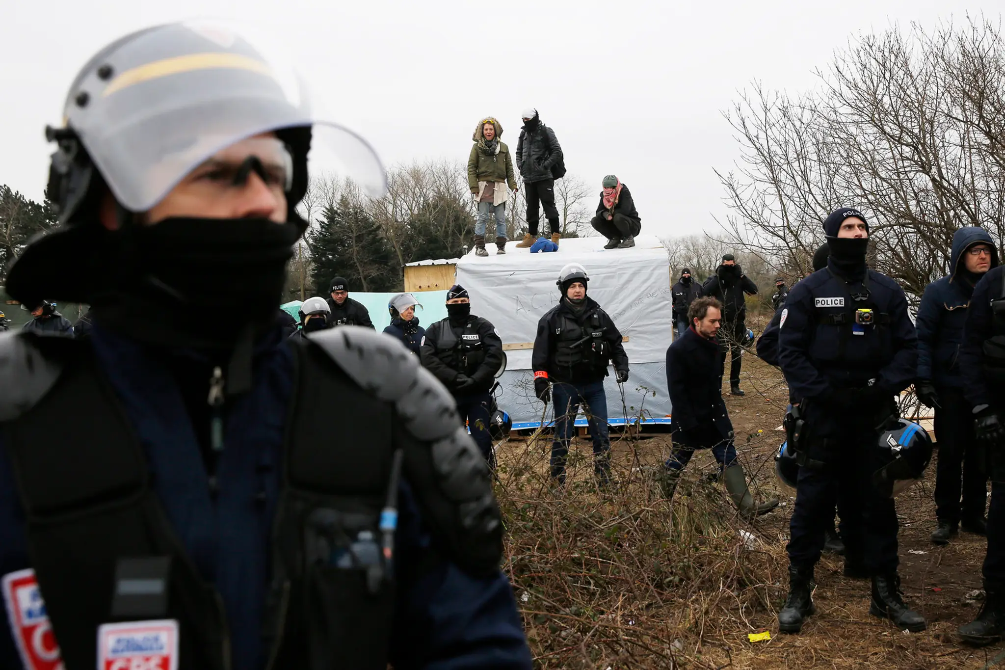 Migranti v tábore pri Calais protestujú na strechách búd.