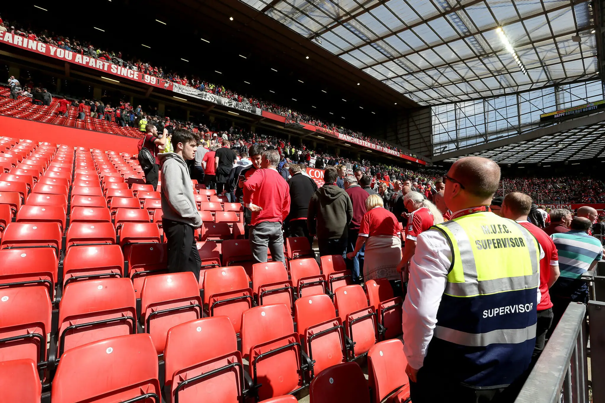 Futbaloví fanúšikovia opúšťajú štadión Old Trafford.