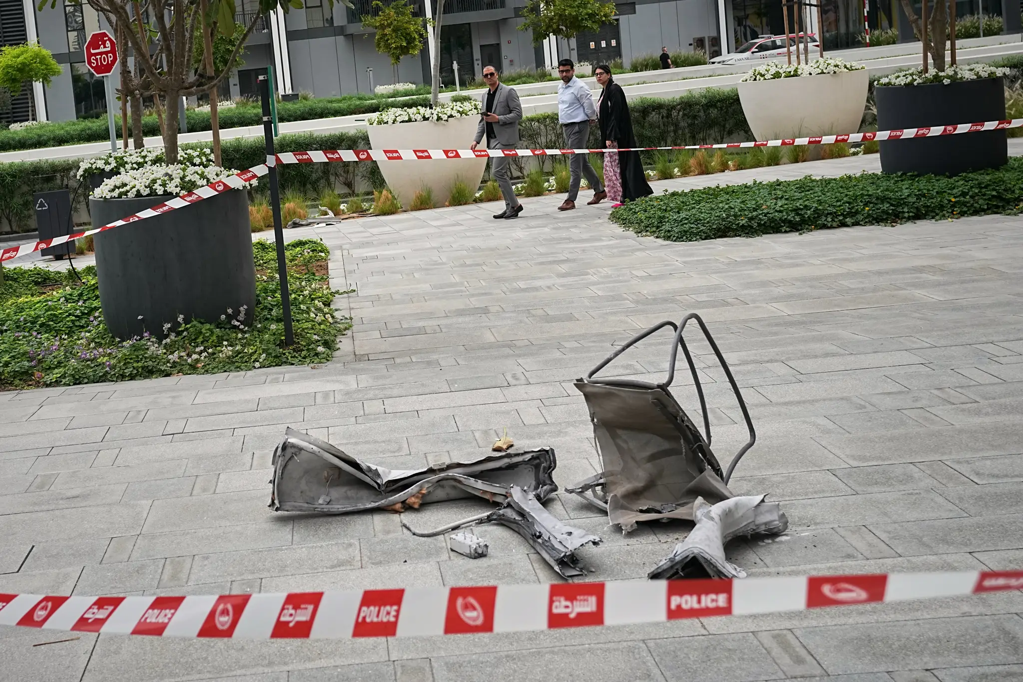Okoloidúci sa pozerajú na trosky ležiace na chodníku pri hoteli Address Creek Harbour po tom, ako ho zasiahol iránsky dron v Dubaji.