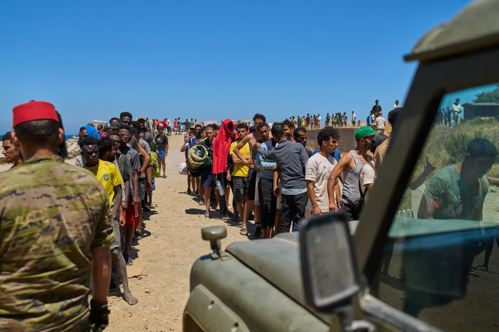 Migranti, ktorí prekročili hranice do Španielska z Maroka, čakajú v rade na vodu, ktorú rozdávajú španielski vojaci.