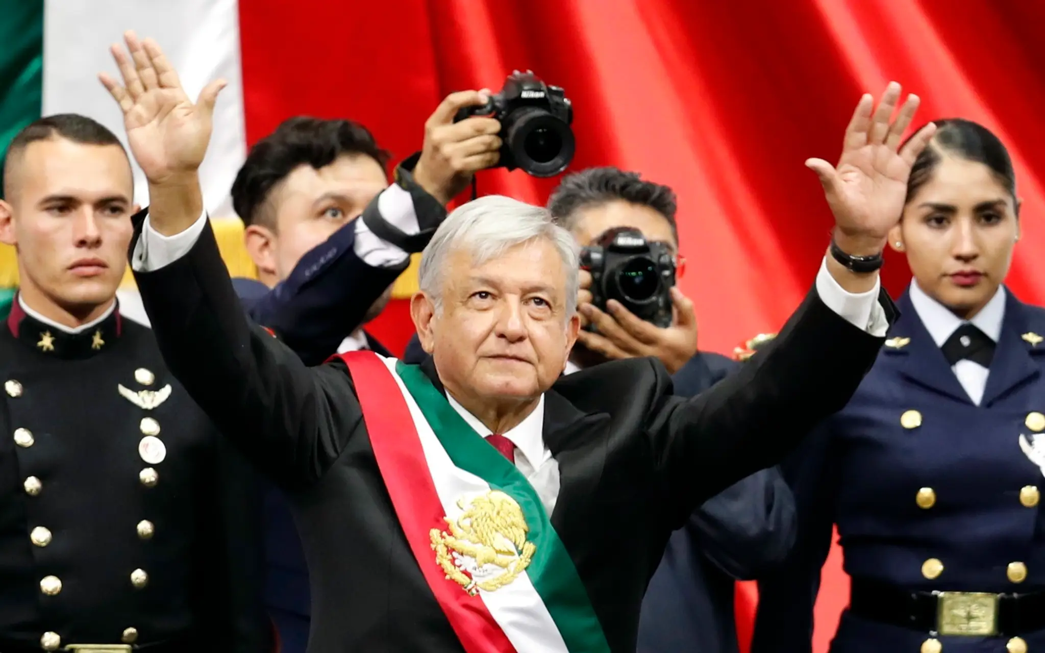 Nový mexický prezident Andrés Manuel López Obrador s prezidentskou stuhou zdraví dav ľudí po jeho prísahe.
