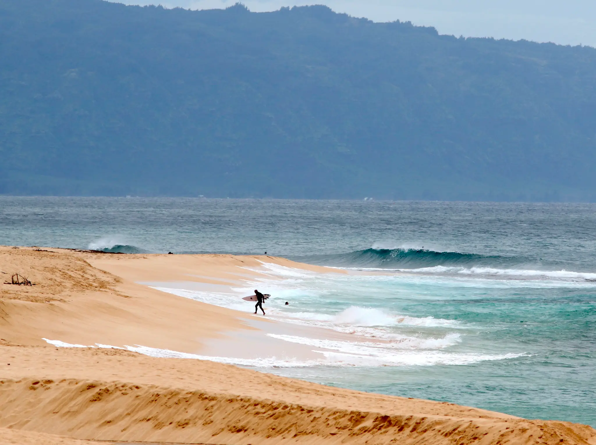 Surfer vychádza z oceánu na severnom pobreží Oahu neďaleko Haleiwa na Havaji.