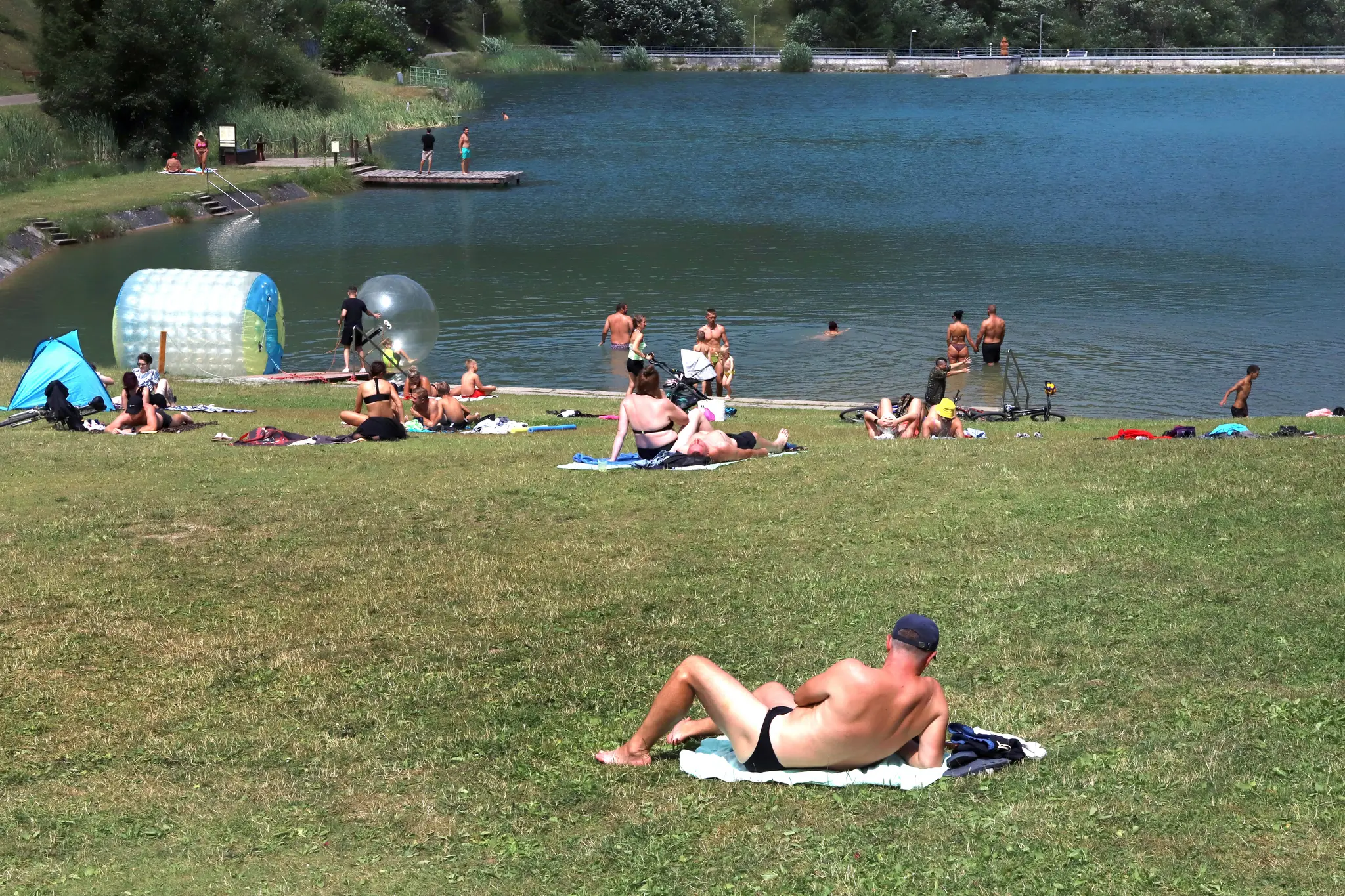 Na snímke ľudia sa kúpu a opaľujú počas letného dňa na vodnej nádrži Hrabovo.