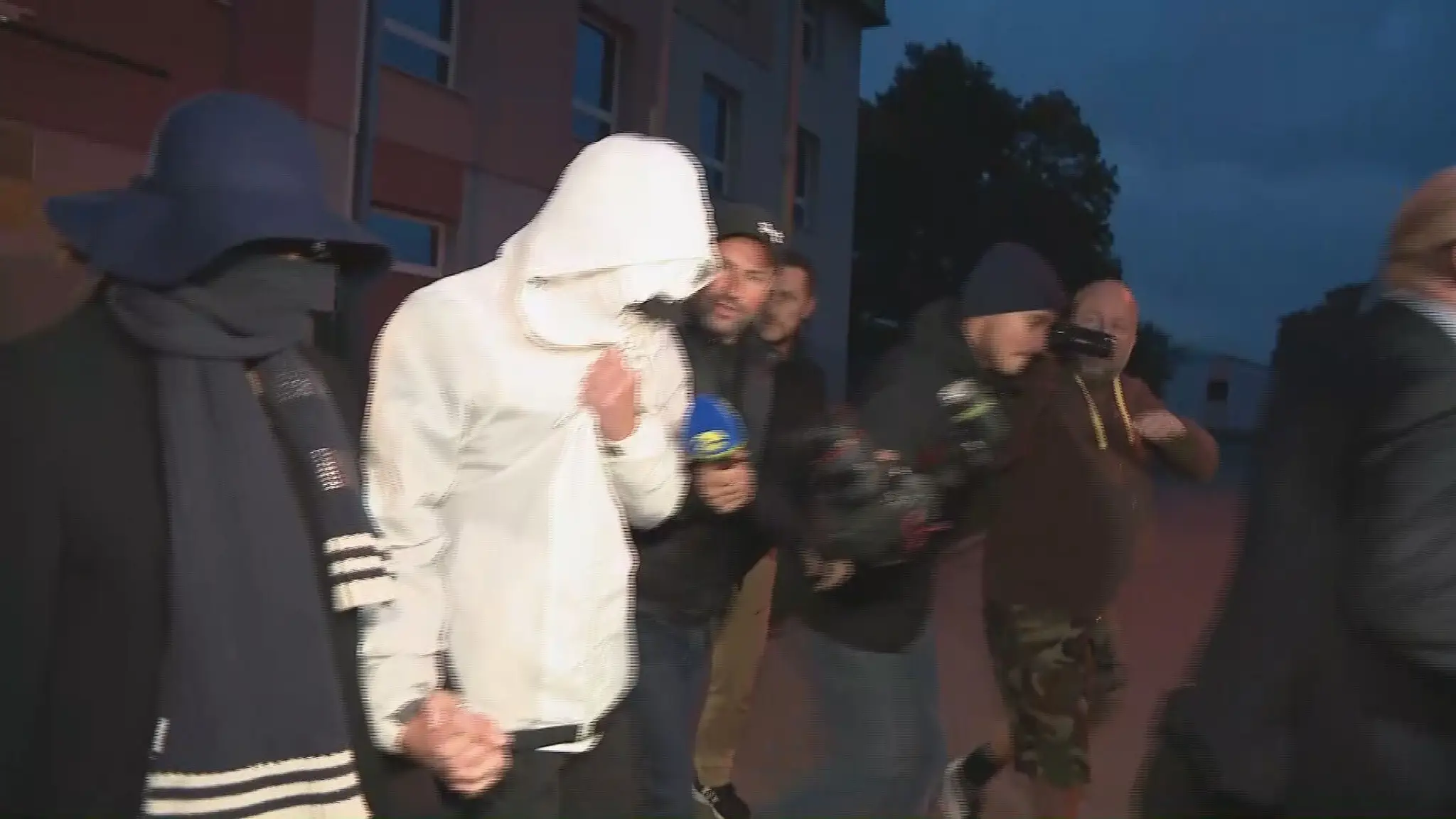 Mladík obvinený z terorizmu odchádza zo súdu so svojou mamou.