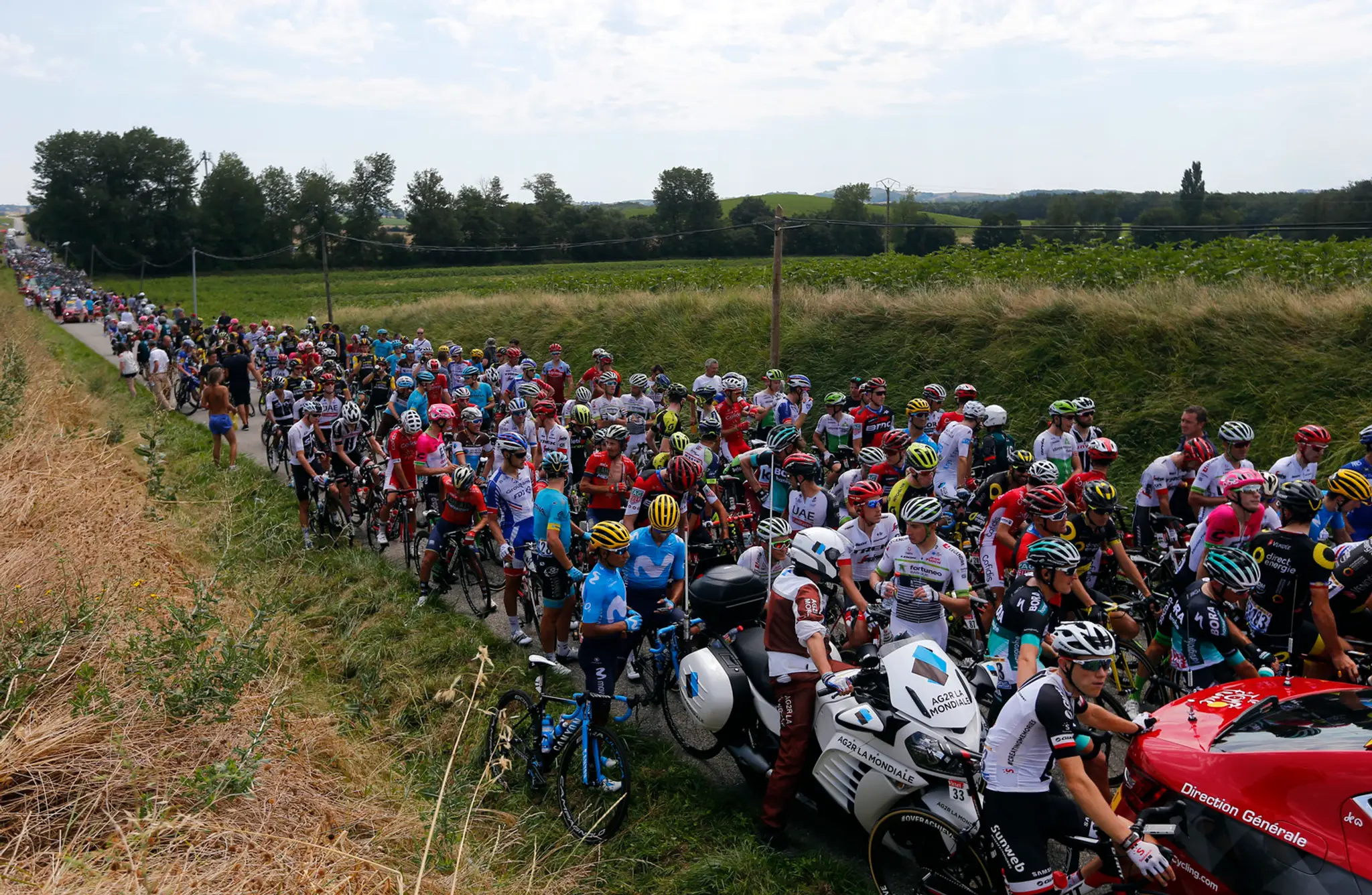 Cyklisti čakajú po tom, čo 16. etapu Tour de France prerušil protest farmárov.