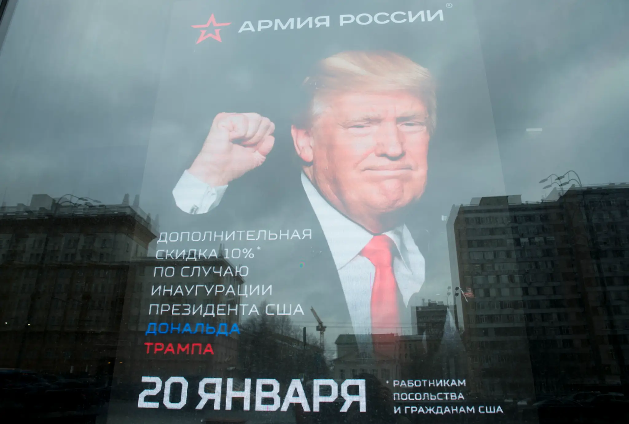 Budova veľvyslanectva USA sa odráža na okne obchodu s plagátom Donalda Trumpa v Moskve.
