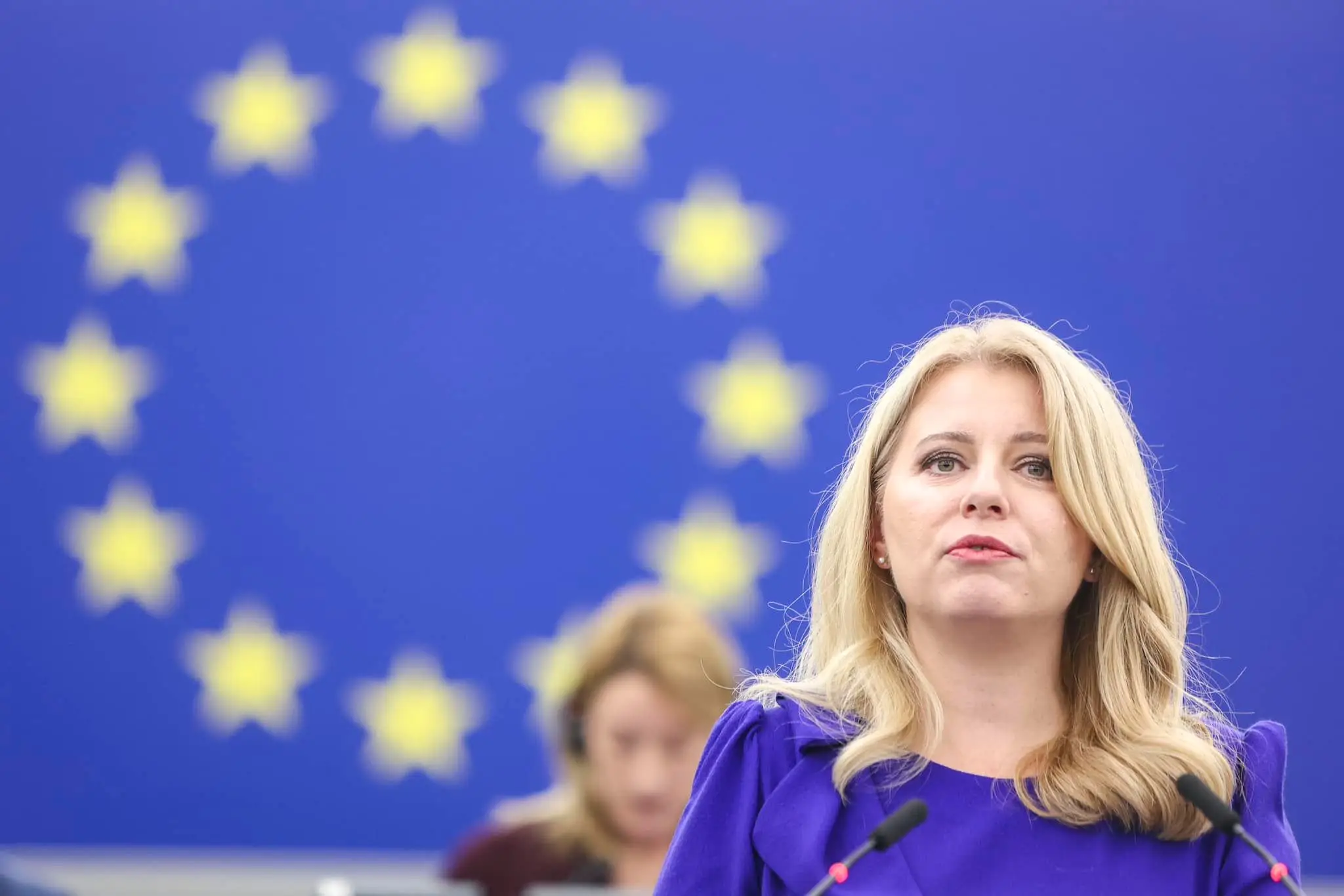 NA snímke je prezidentka Slovenska Zuzana Čaputová, za sebou má modré pozadie s hviezdami, vlajku Európskej únie.