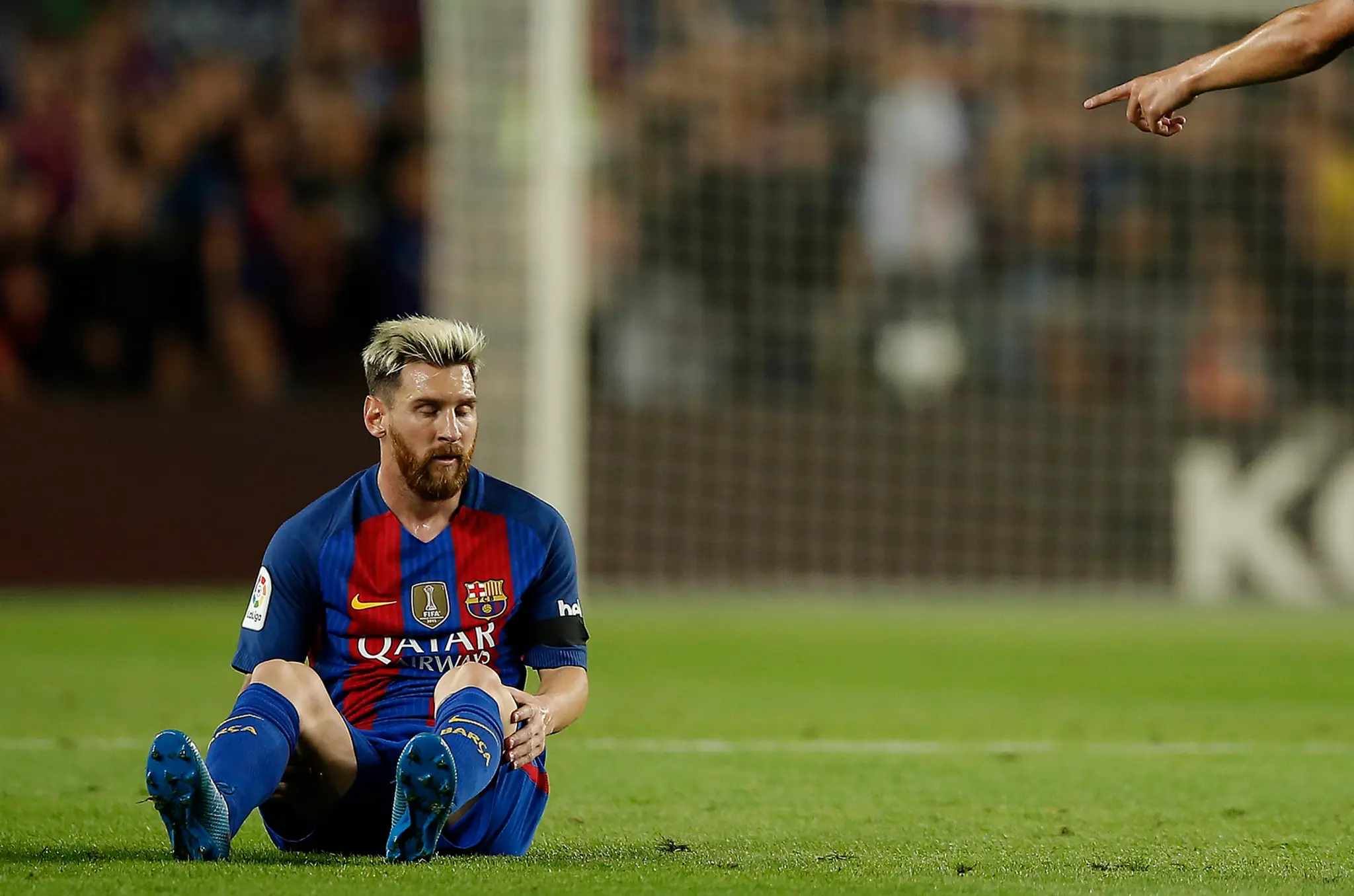 Lionel Messi sedí na trávniku 