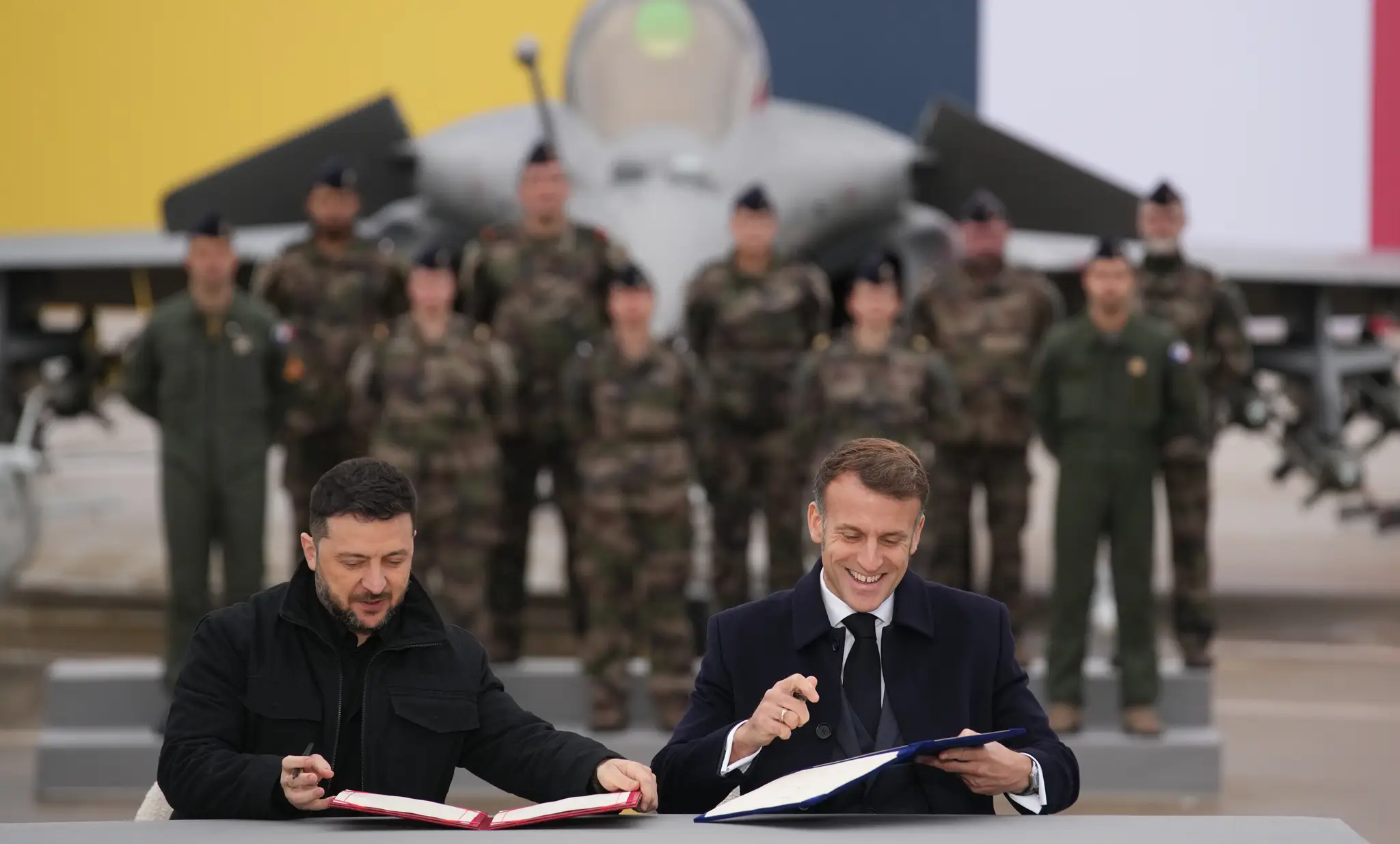Francúzsky prezident Emmanuel Macron (vpravo) a ukrajinský prezident Volodymyr Zelenskyj podpisujú dohodu o nákupe stíhačiek Rafale.
