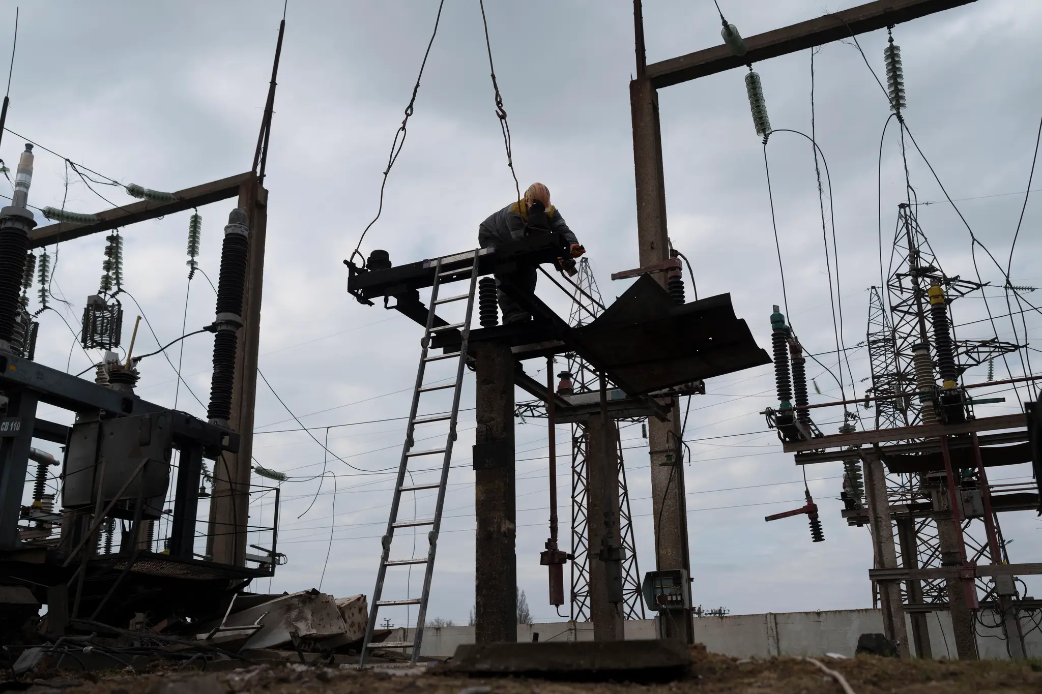 Pracovník DTEK pracuje na poškodenom mieste po ruskom dronovom útoku na elektrickú rozvodňu na neznámom mieste na Ukrajine.