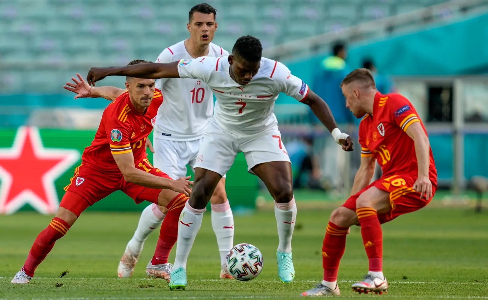 Breel Embolo, v strede, v súboji o loptu s Aaronom Ramseyom a Joeom Moreellom.