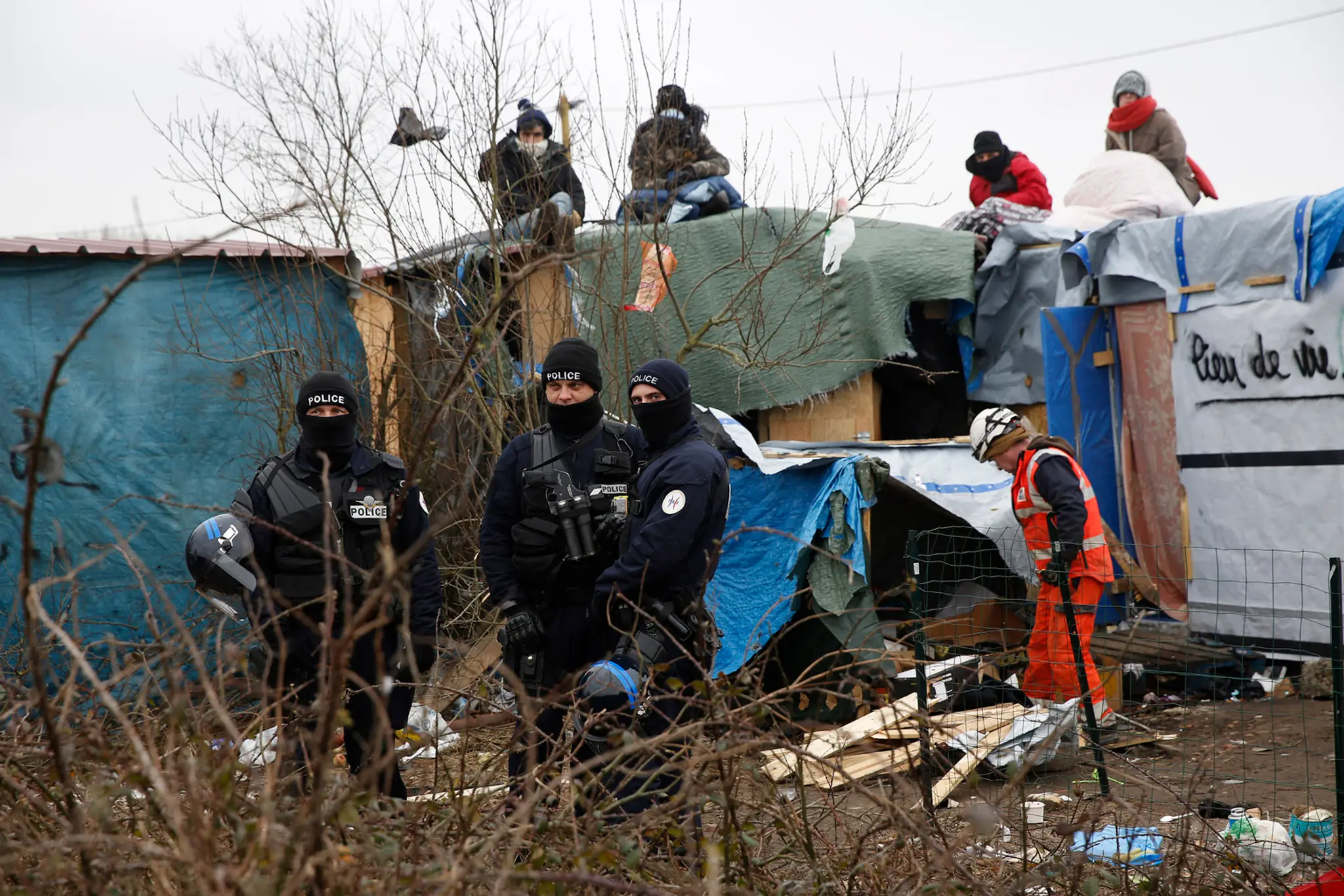 Migranti v tábore pri Calais protestujú na strechách búd.