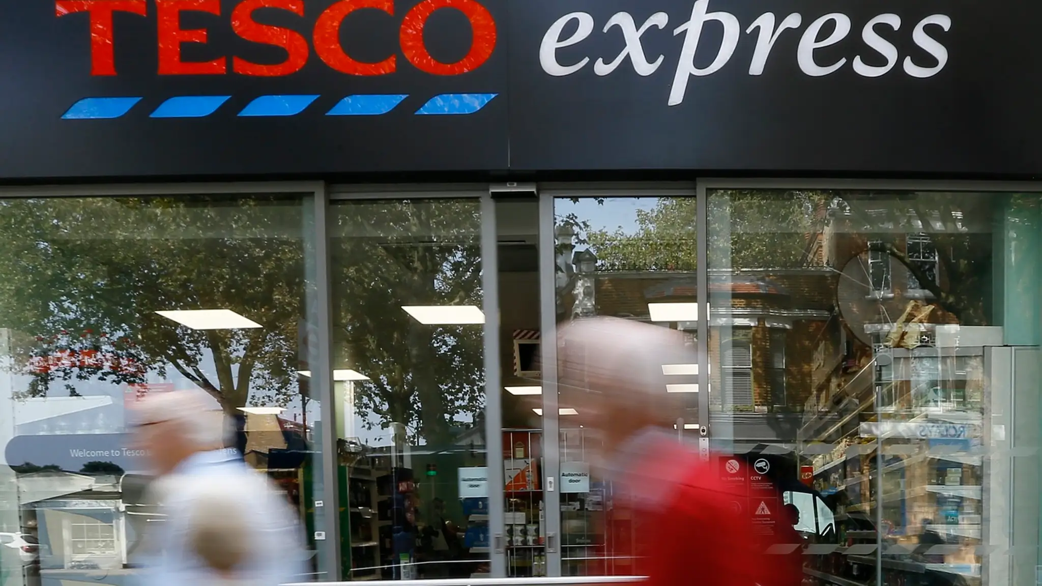 Ľudia prechádzajú okolo obchodu Tesco express.
